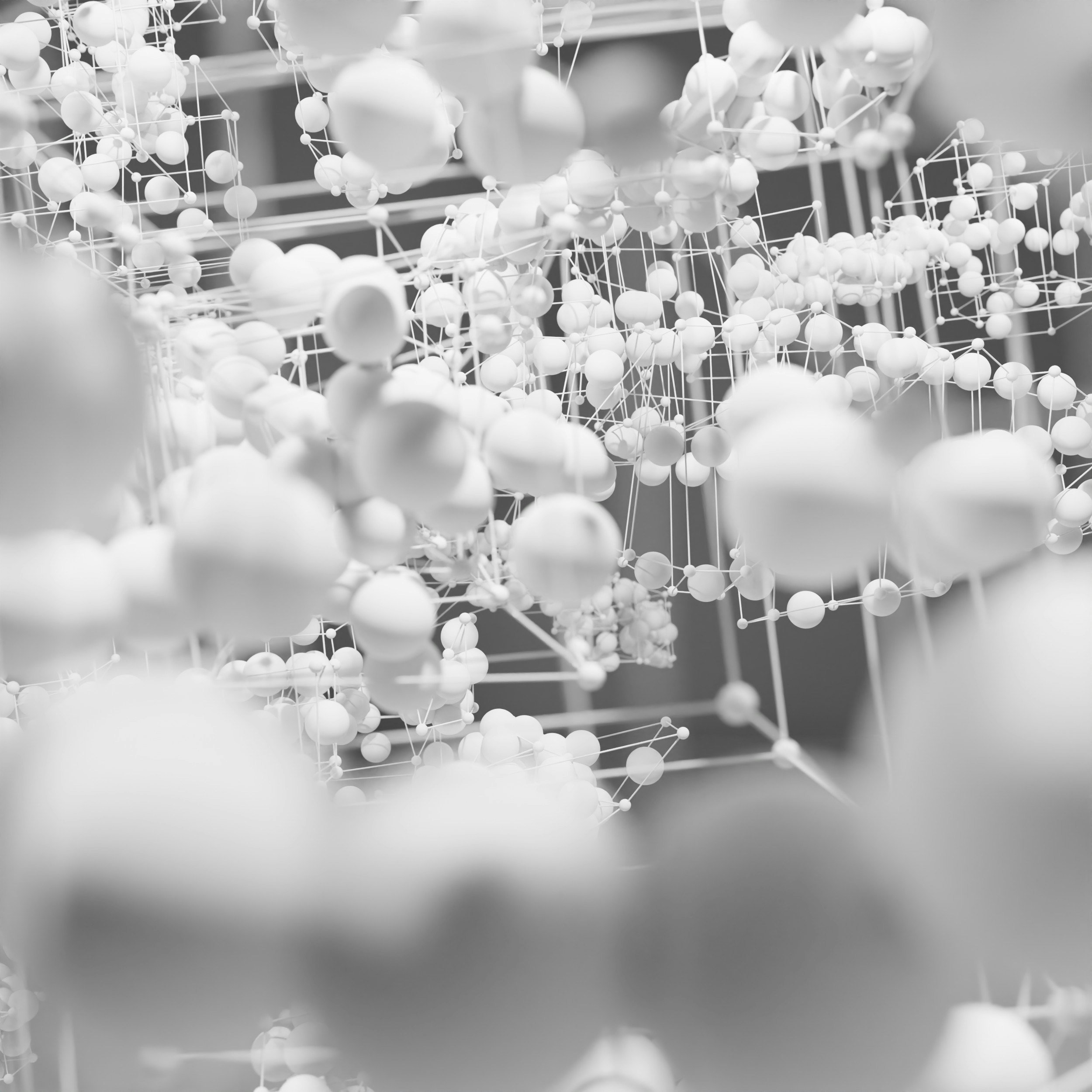 A close-up of a complex molecular model or artistic representation of atoms connected by bonds, depicted in monochrome.