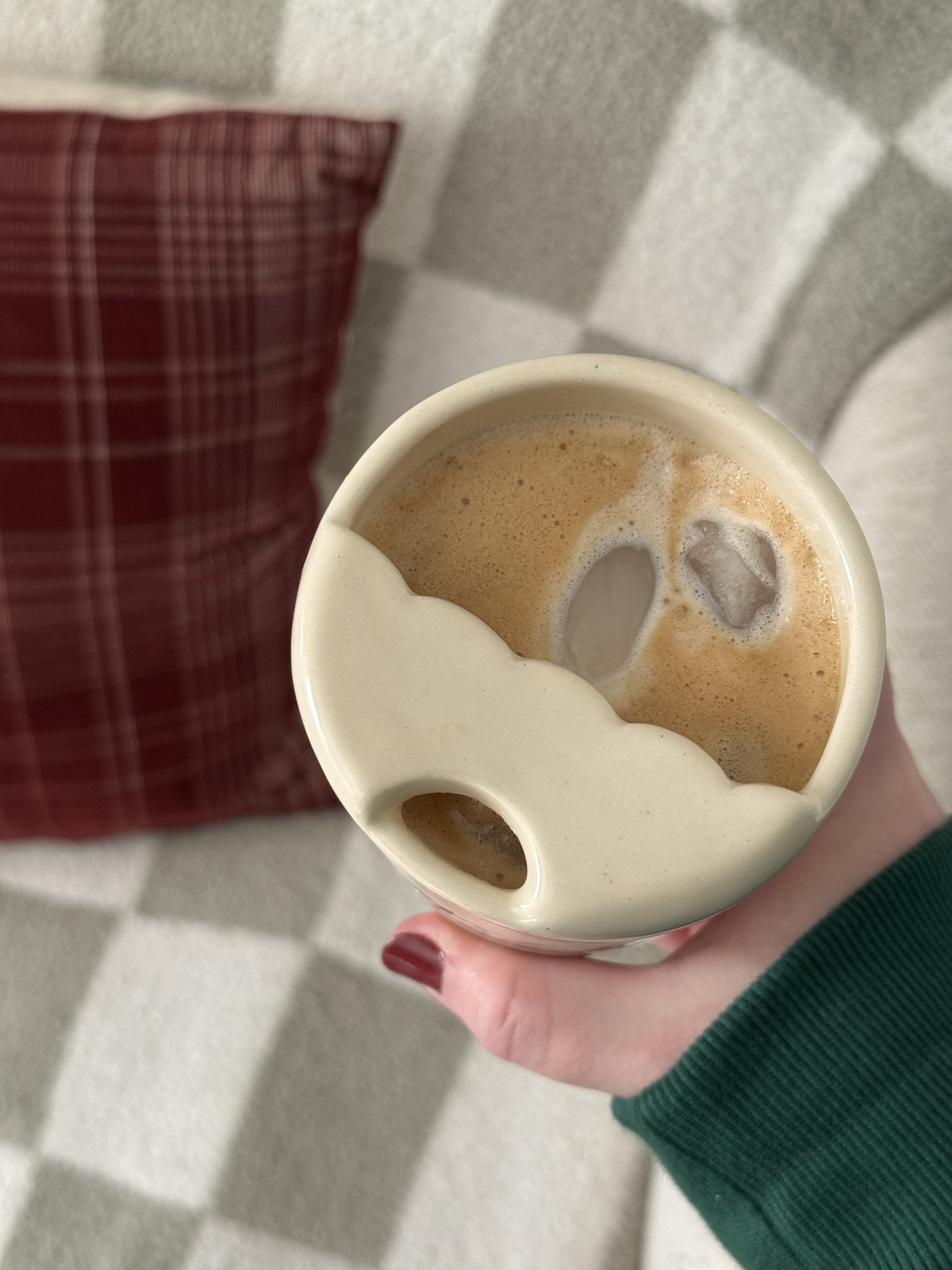 Looking down into a ceramic travel mug filled with iced coffee