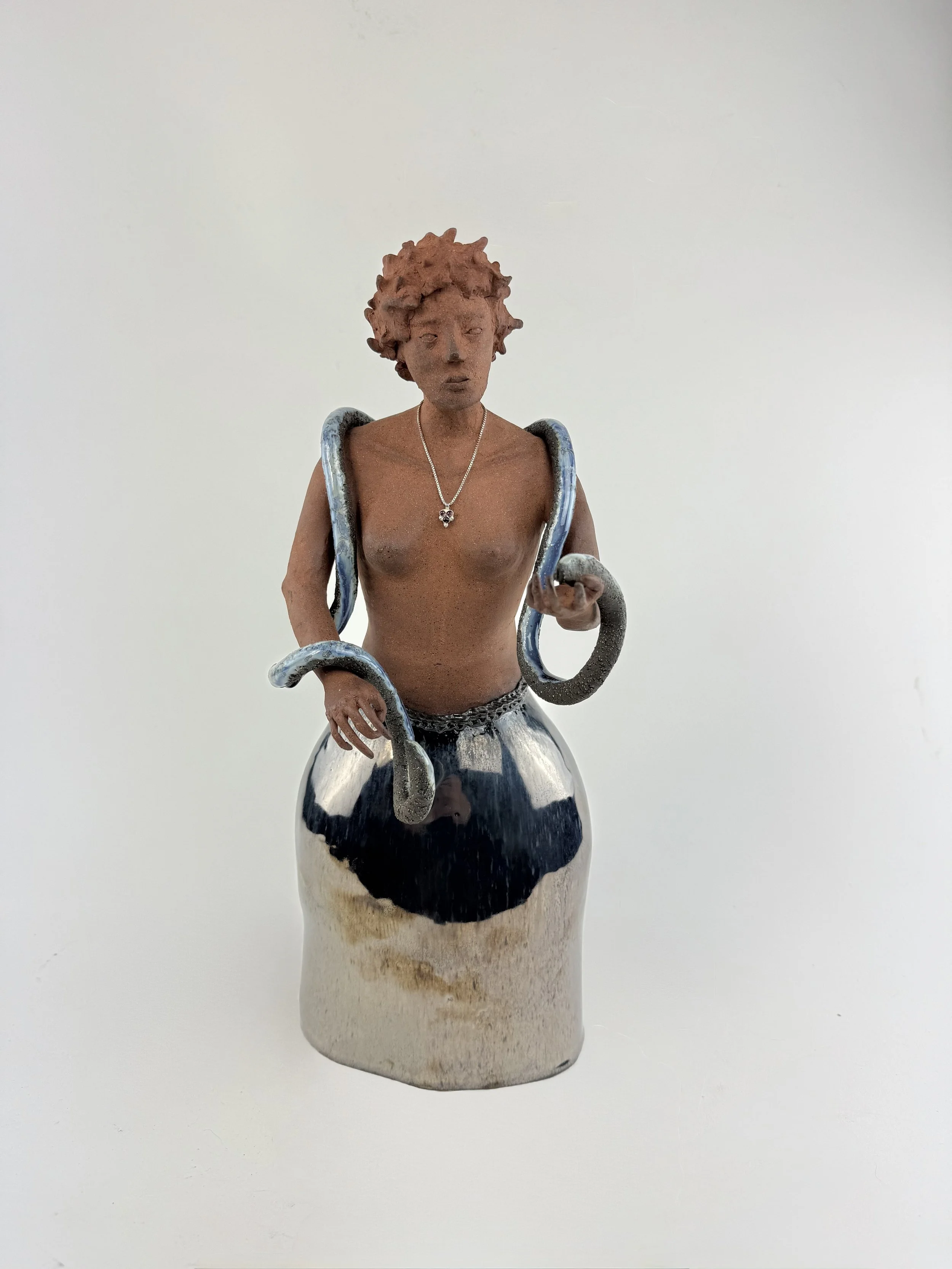 Female ceramic figure with a snake on her shoulders in terra cotta and silver metallic