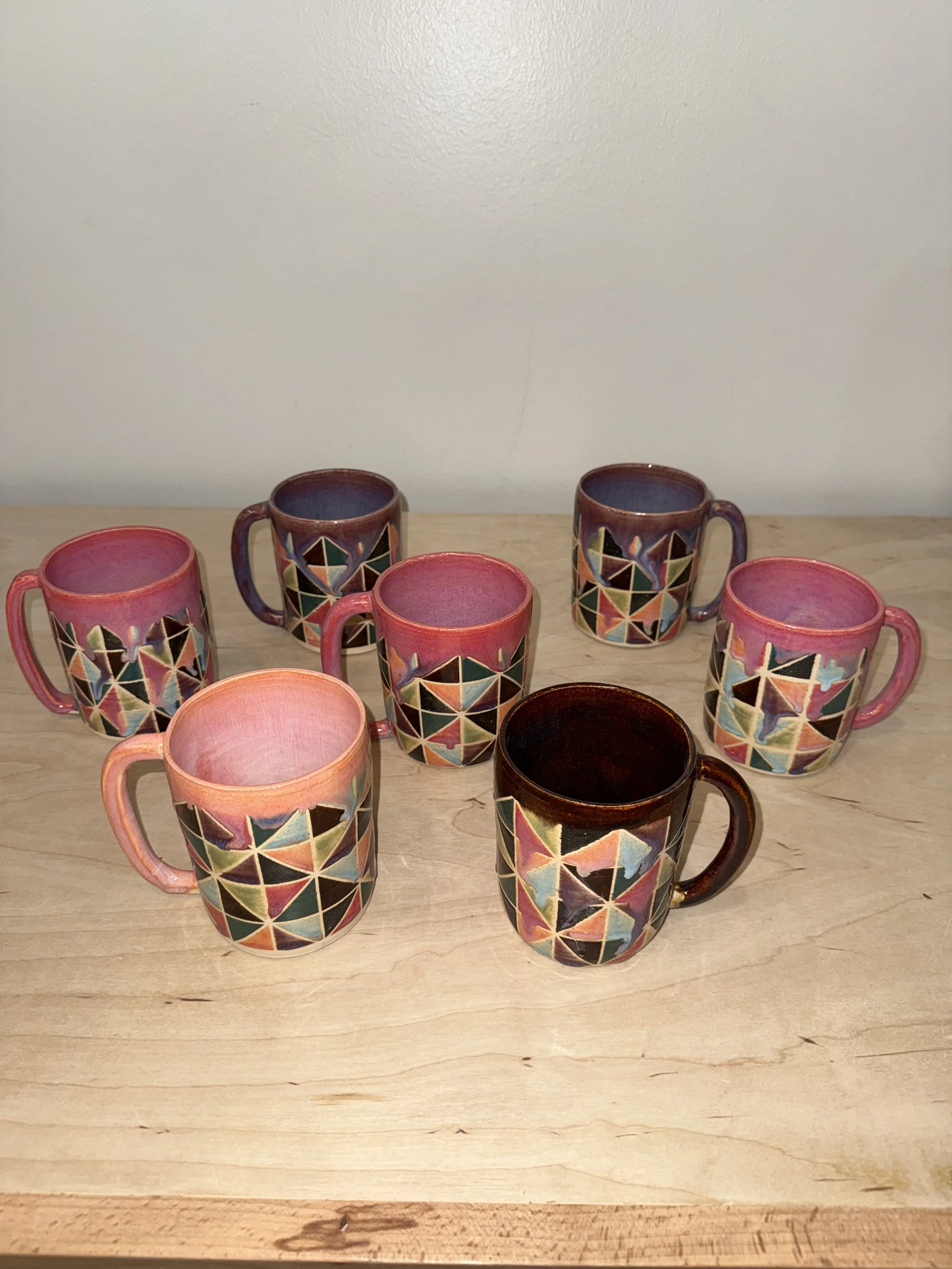 A selection of seven multicolored ceramic mugs with a geometric design