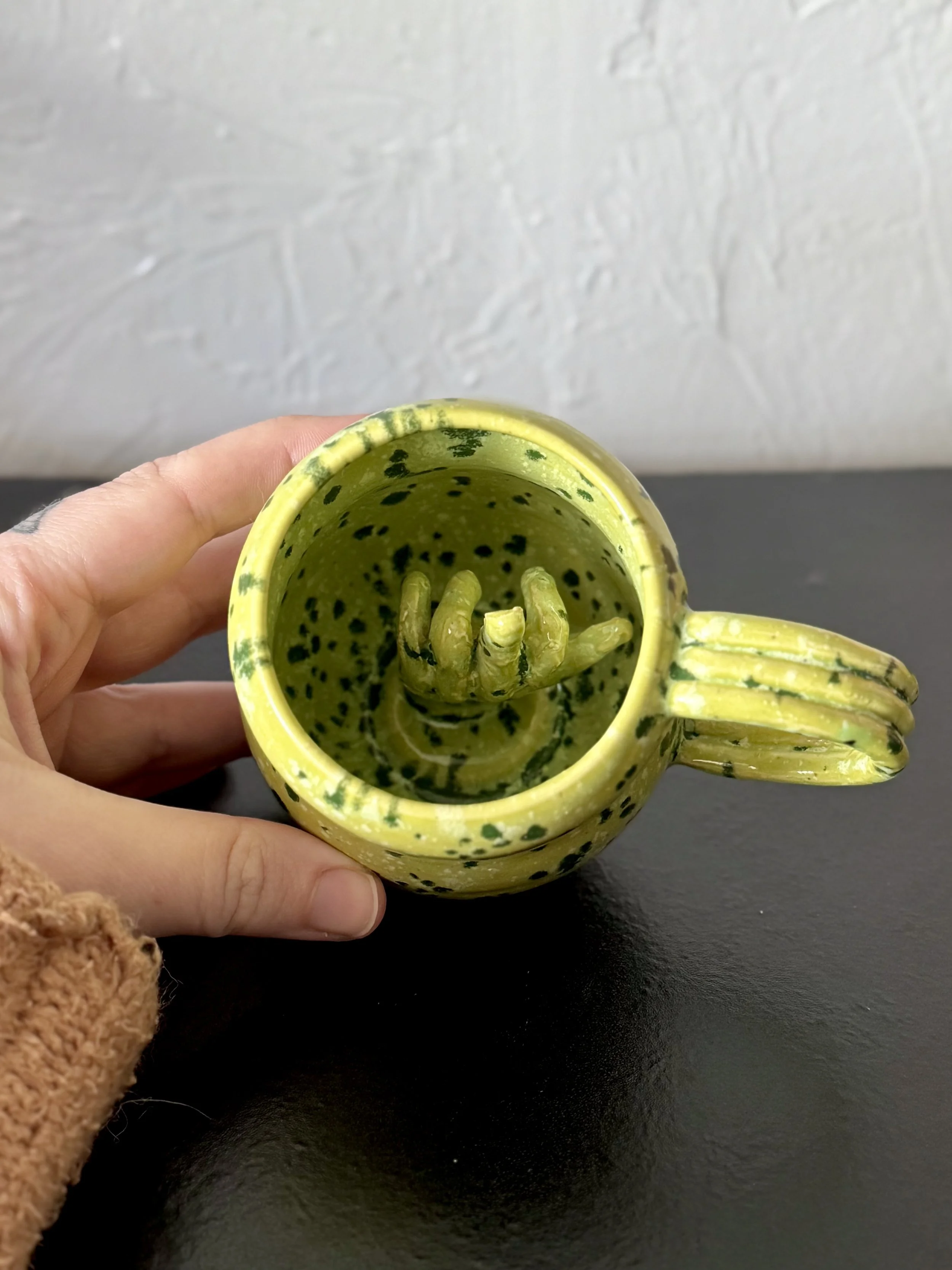 Bright green mug with hand inside