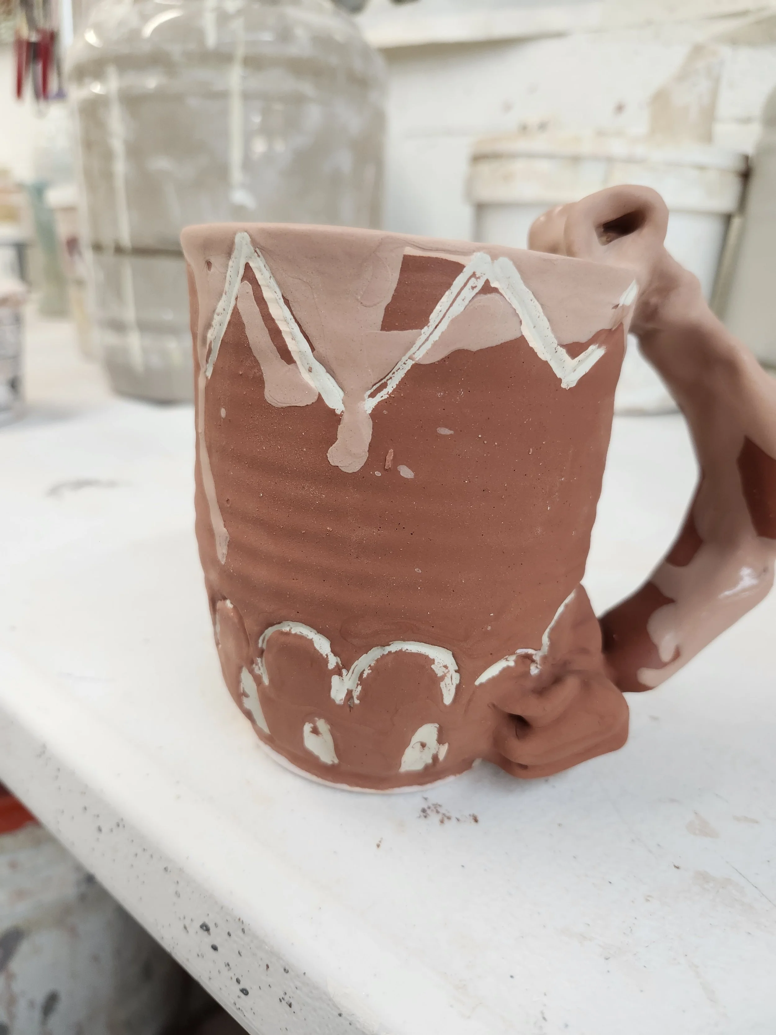 Glazed but unfired coffee mug with a geometric splash design