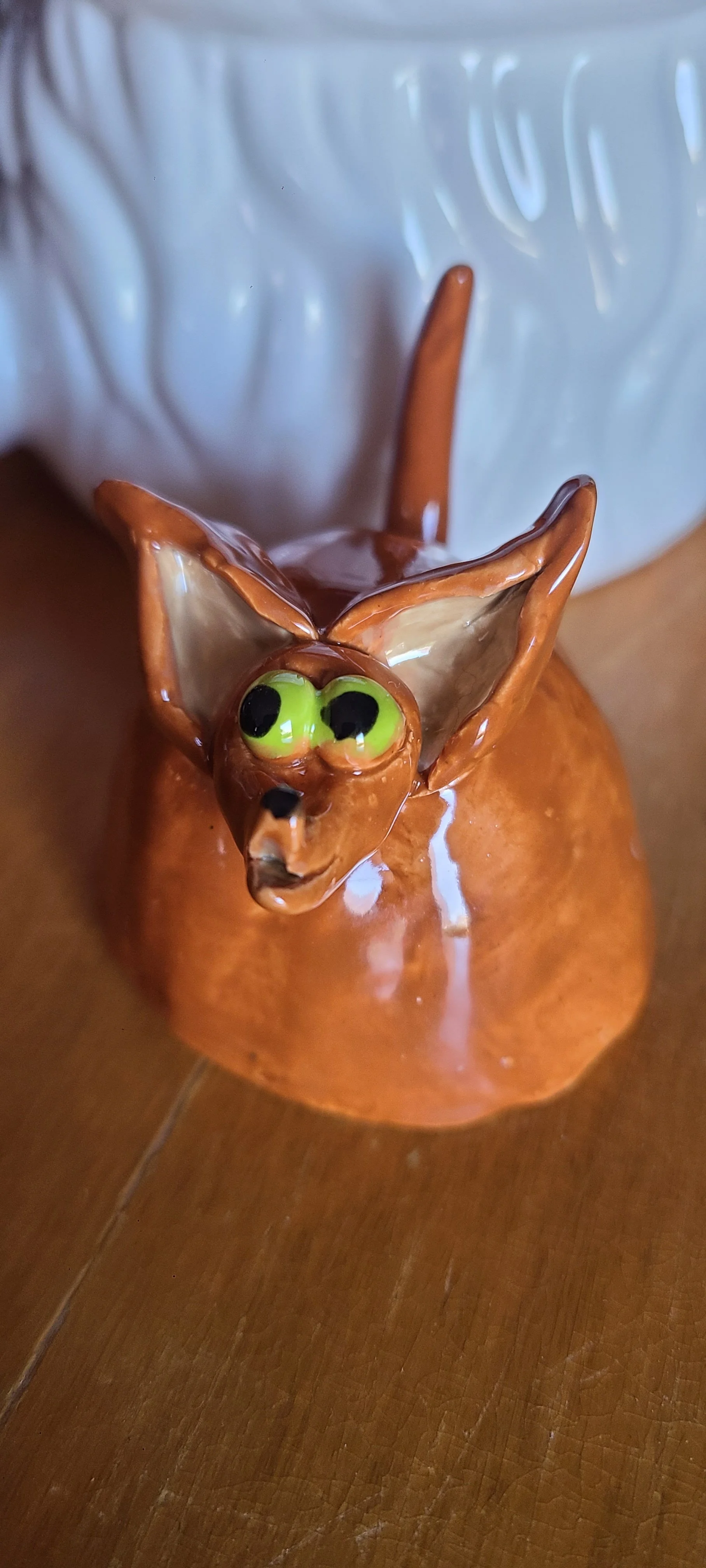 Bat-like ceramic creature with lime green eyes