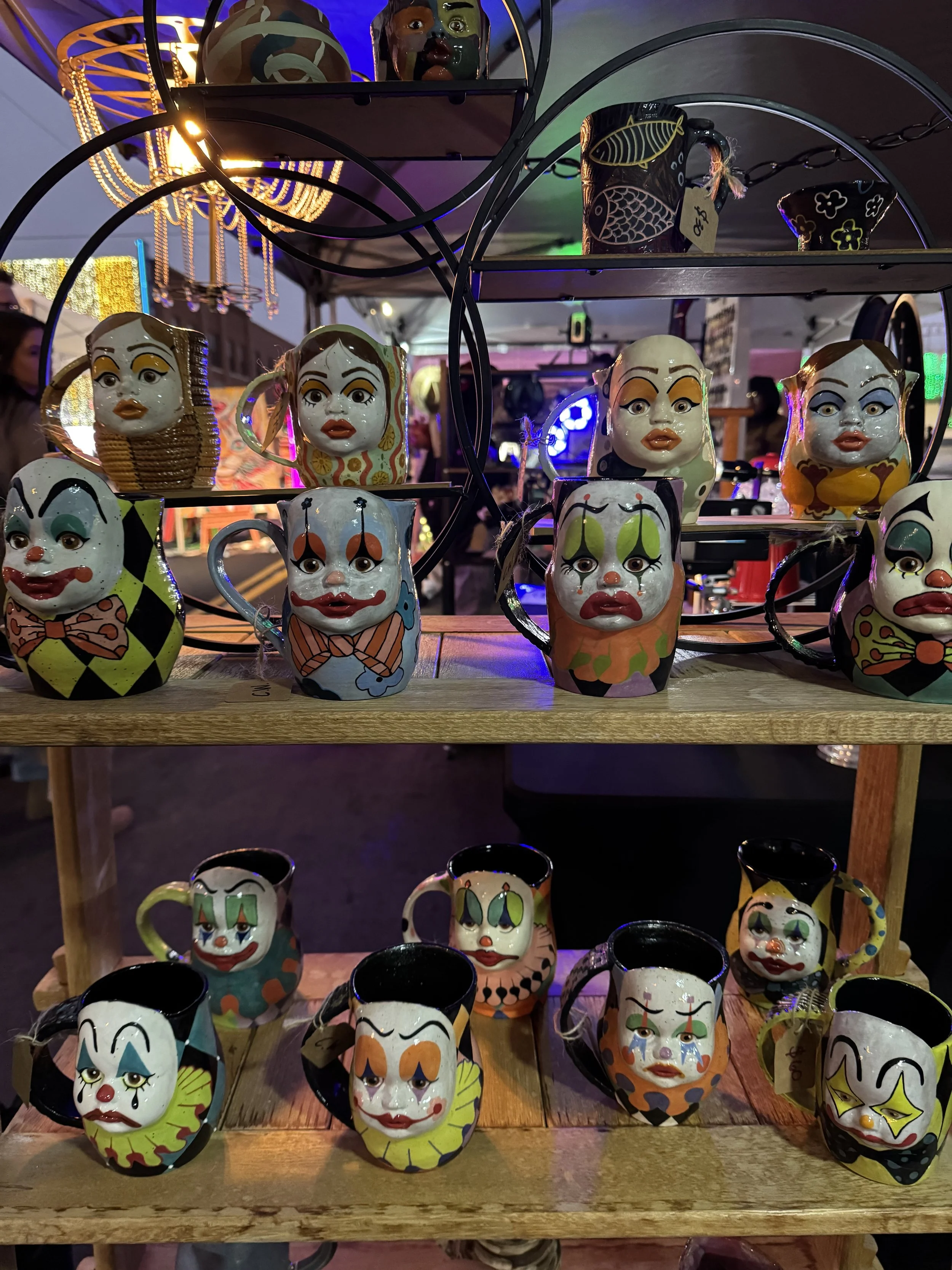 Large selection of ceramic mugs with doll faces in clown makeup