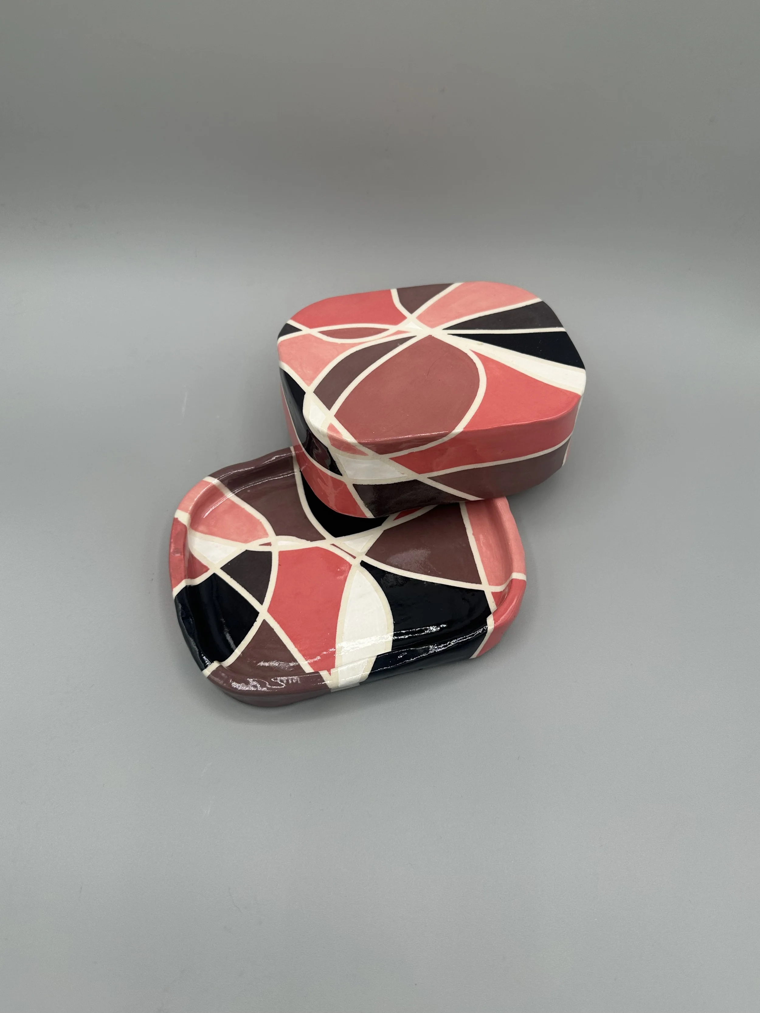 Ceramic covered dish glazed in geometric pinks, browns and black