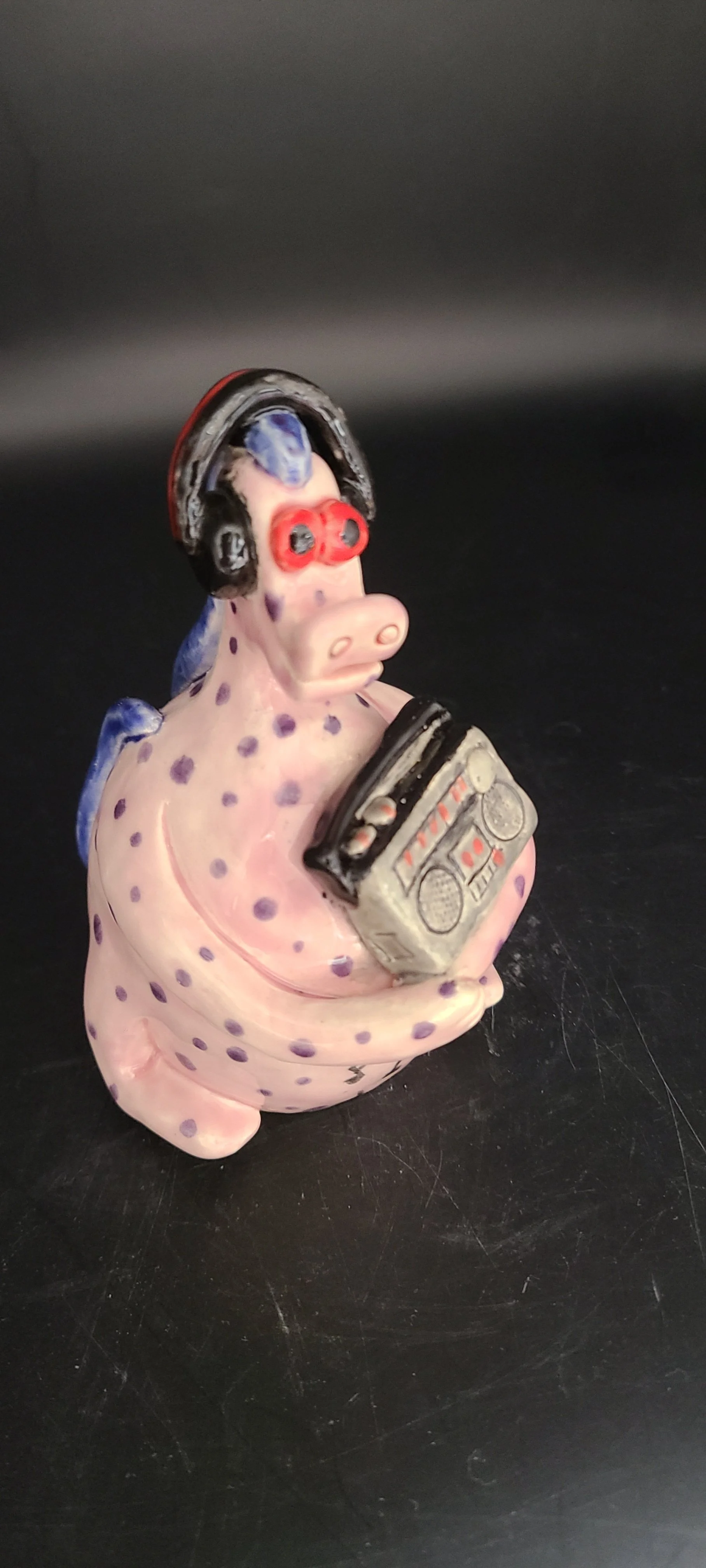 Pink spotted ceramic creature with headphones and radio