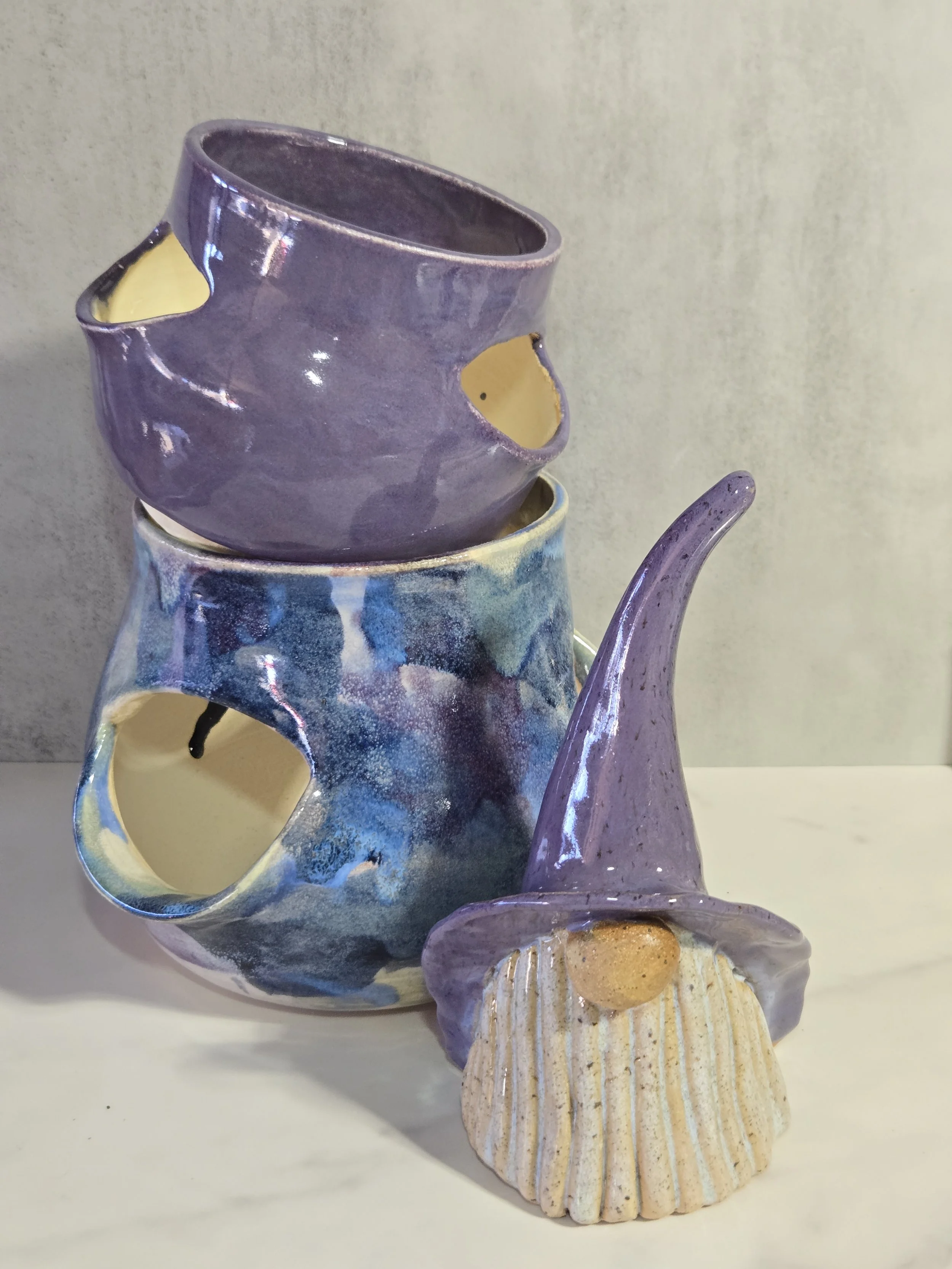 Two ceramic strawberry pots in purple and blue and a ceramic gnome with a purple hat