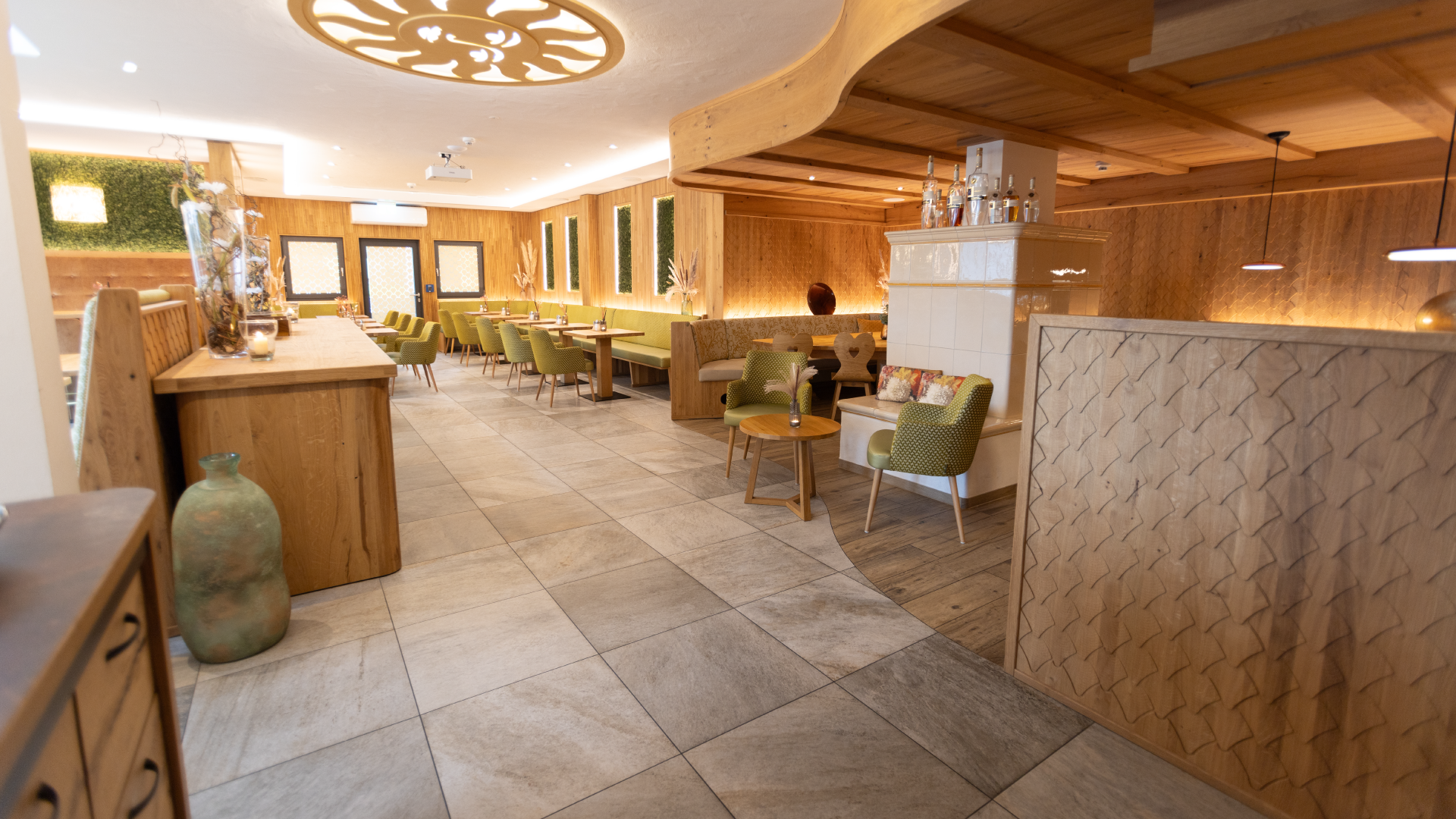 Gemütliches Restaurantinterieur mit Holzelementen, grünen Stühlen und dekorativen Vasen.