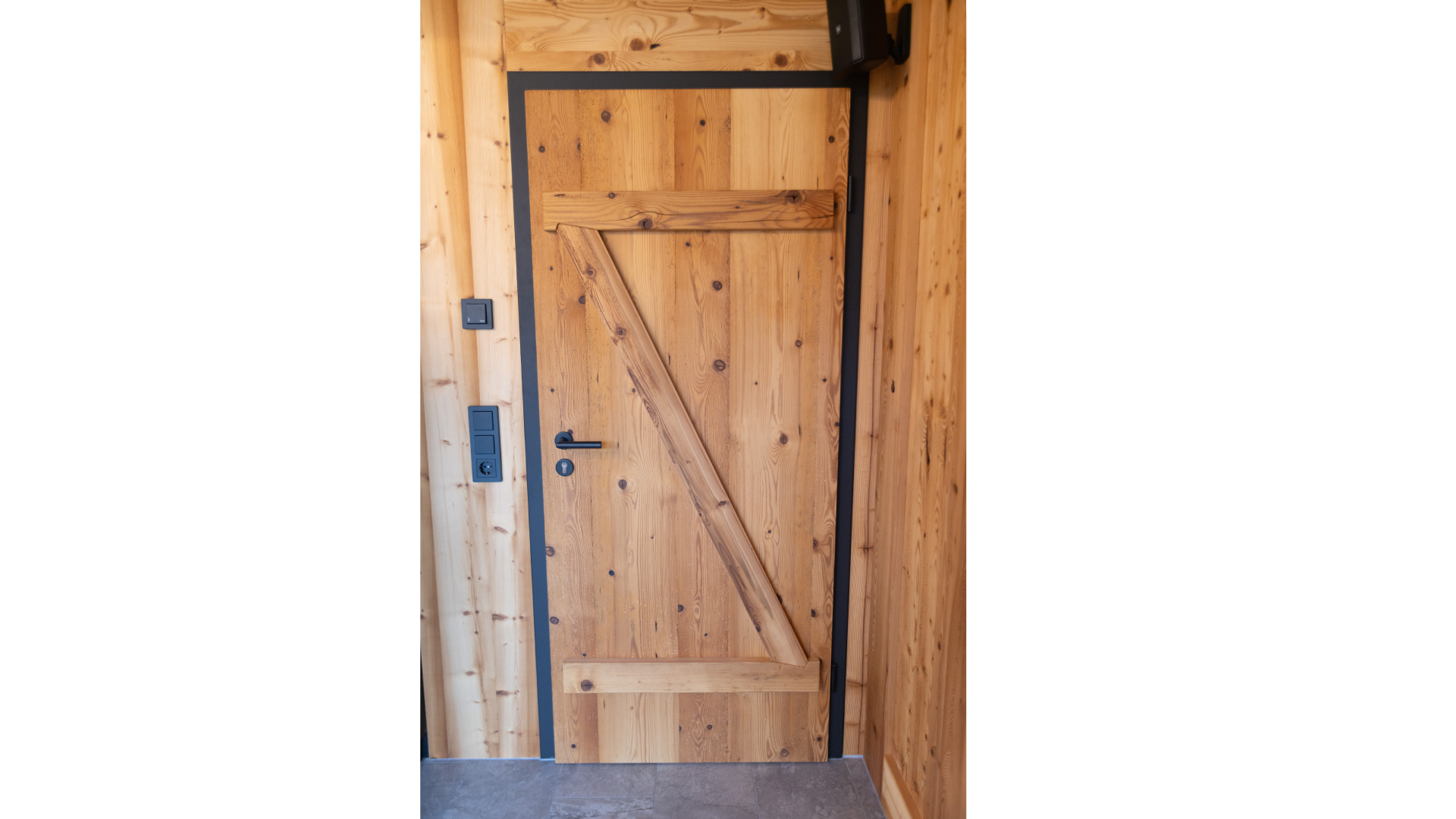 Holztür mit diagonalem Zaun in einem Raum mit Holzpaneelwänden