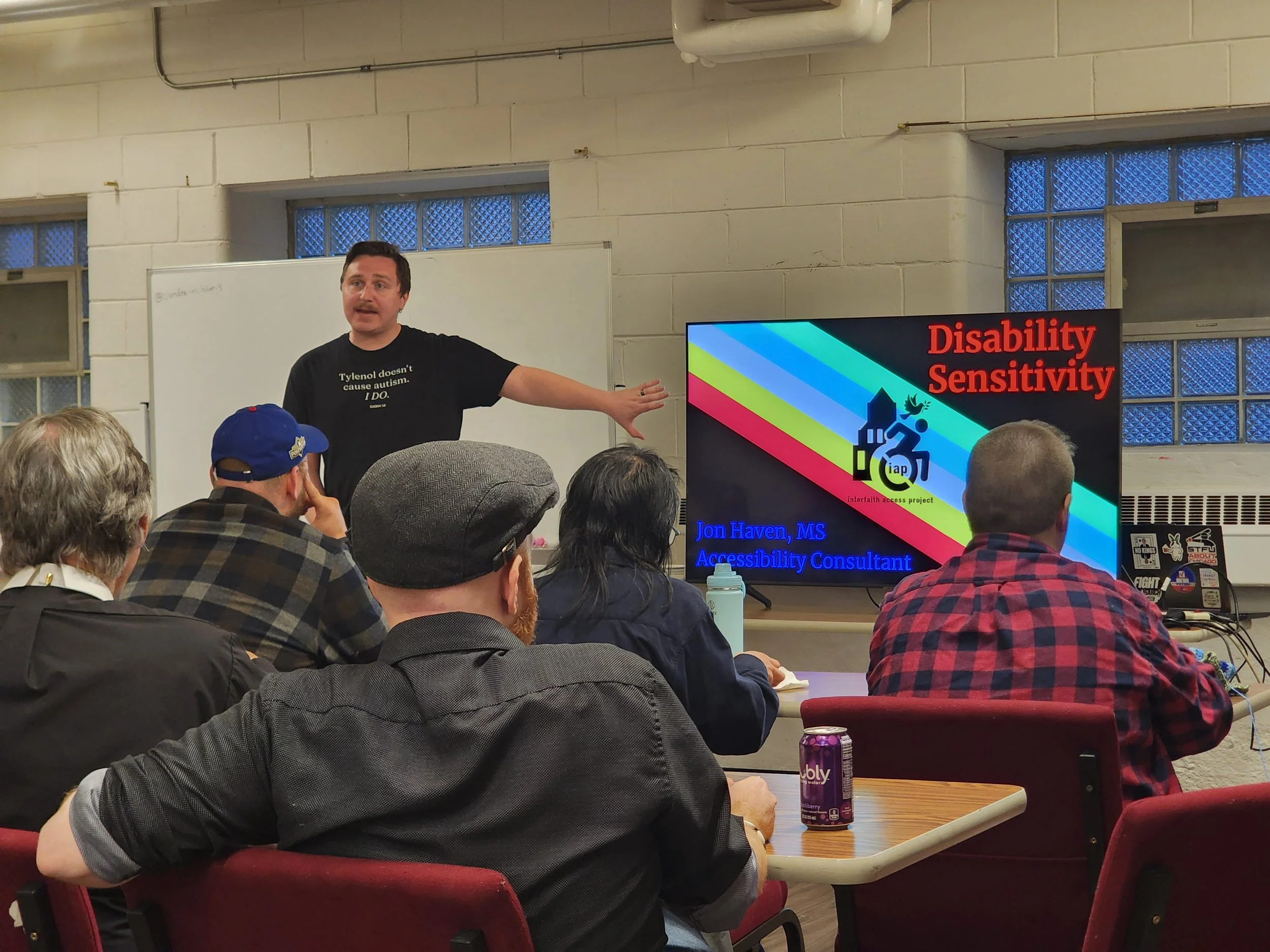Jon stands in front of congregants while pointing at a screen for a presentation.