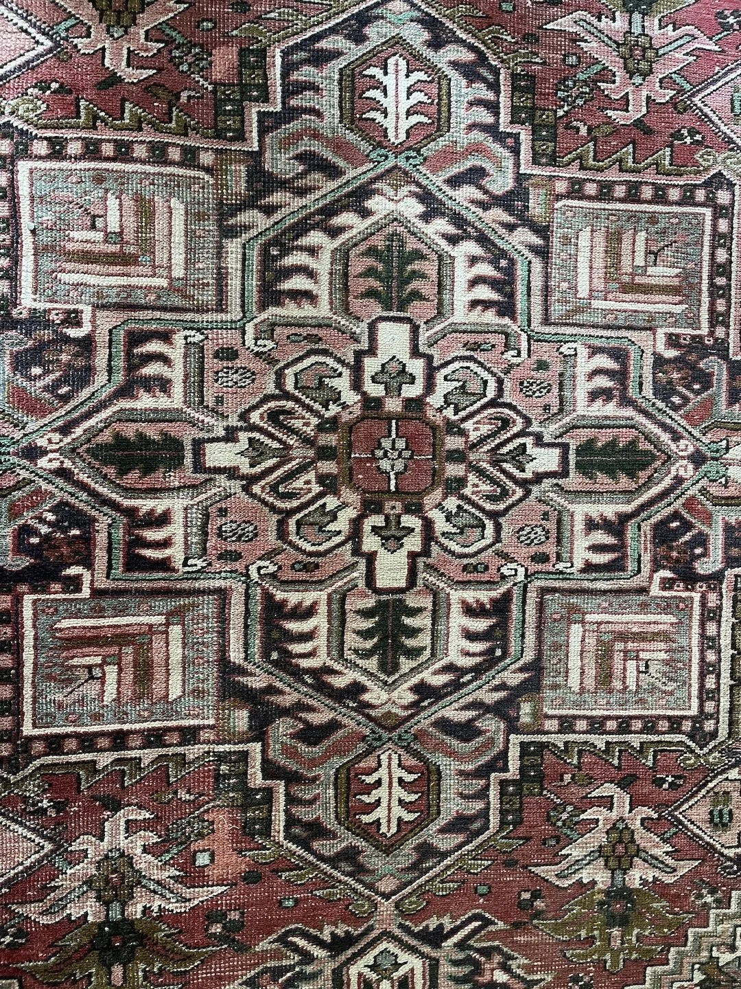 Close-up of a traditional Persian rug with geometric patterns in red, black, white, and green.