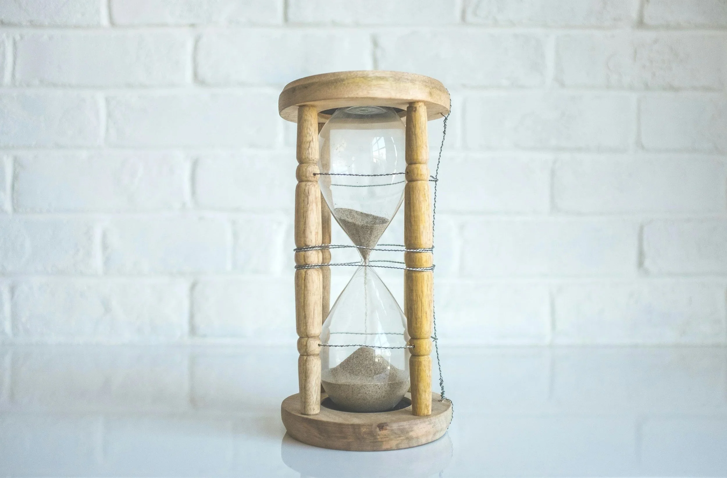 Wooden hourglass with sand inside, representing precious time in supervised visitations with Meghann Shannon Mullet being the founder of Straight Shot Supervision.