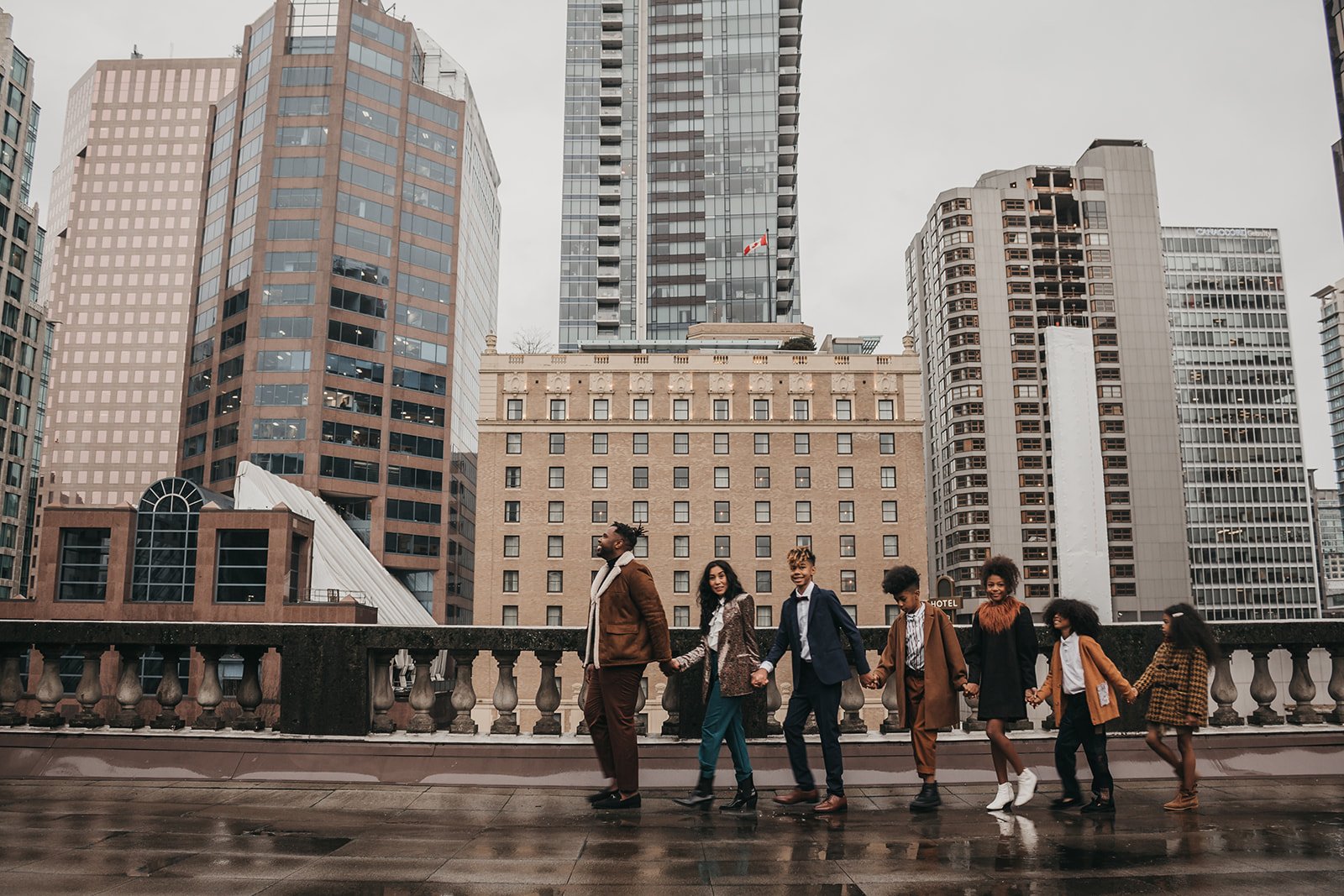 Group of people holding hands walking in front of city skyline with modern high-rise buildings.