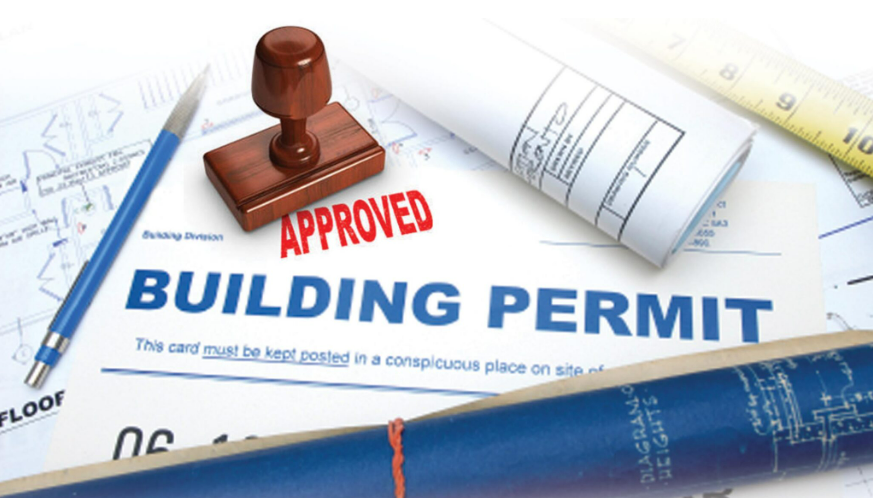 Approved building permit document with a stamp, blueprints, a pen, and technical drawings on a table.
