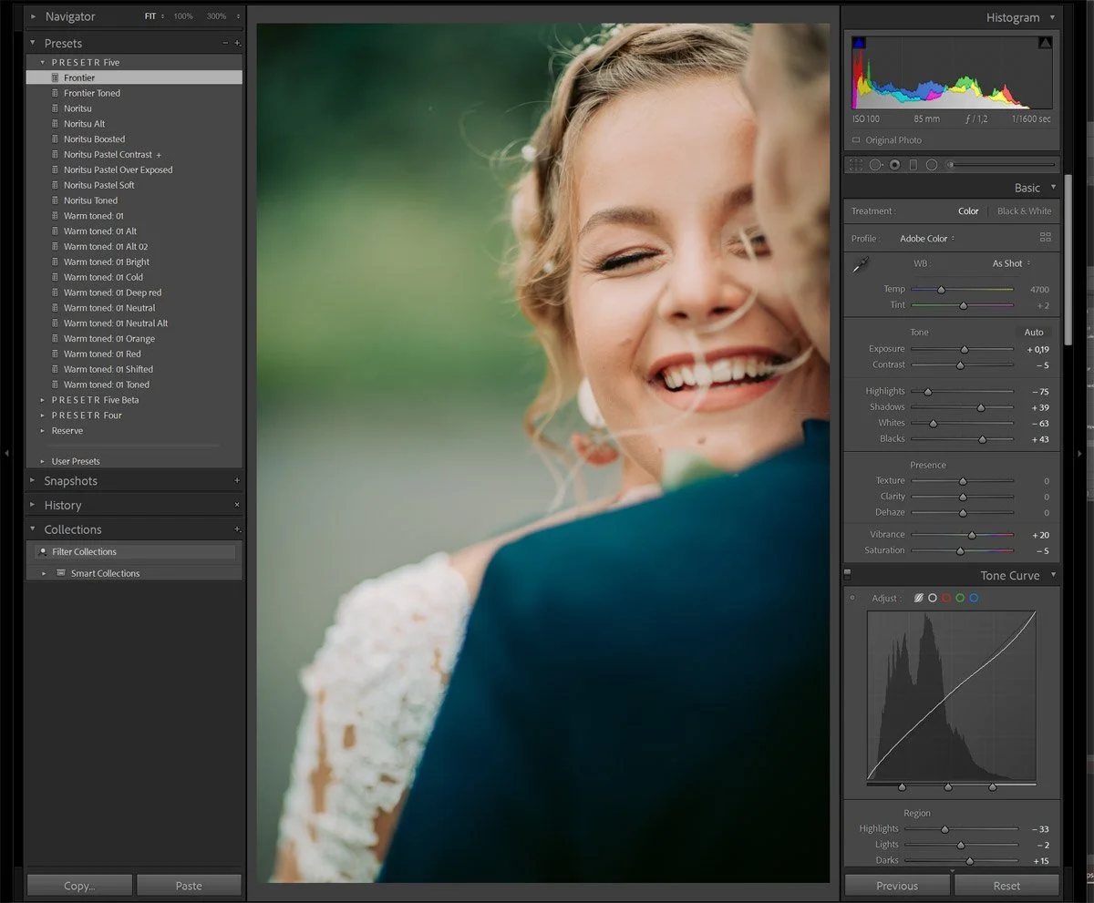 A woman smiling and laughing, with her eyes closed, during a joyful moment, possibly at a wedding or celebration, with a green blurred background.