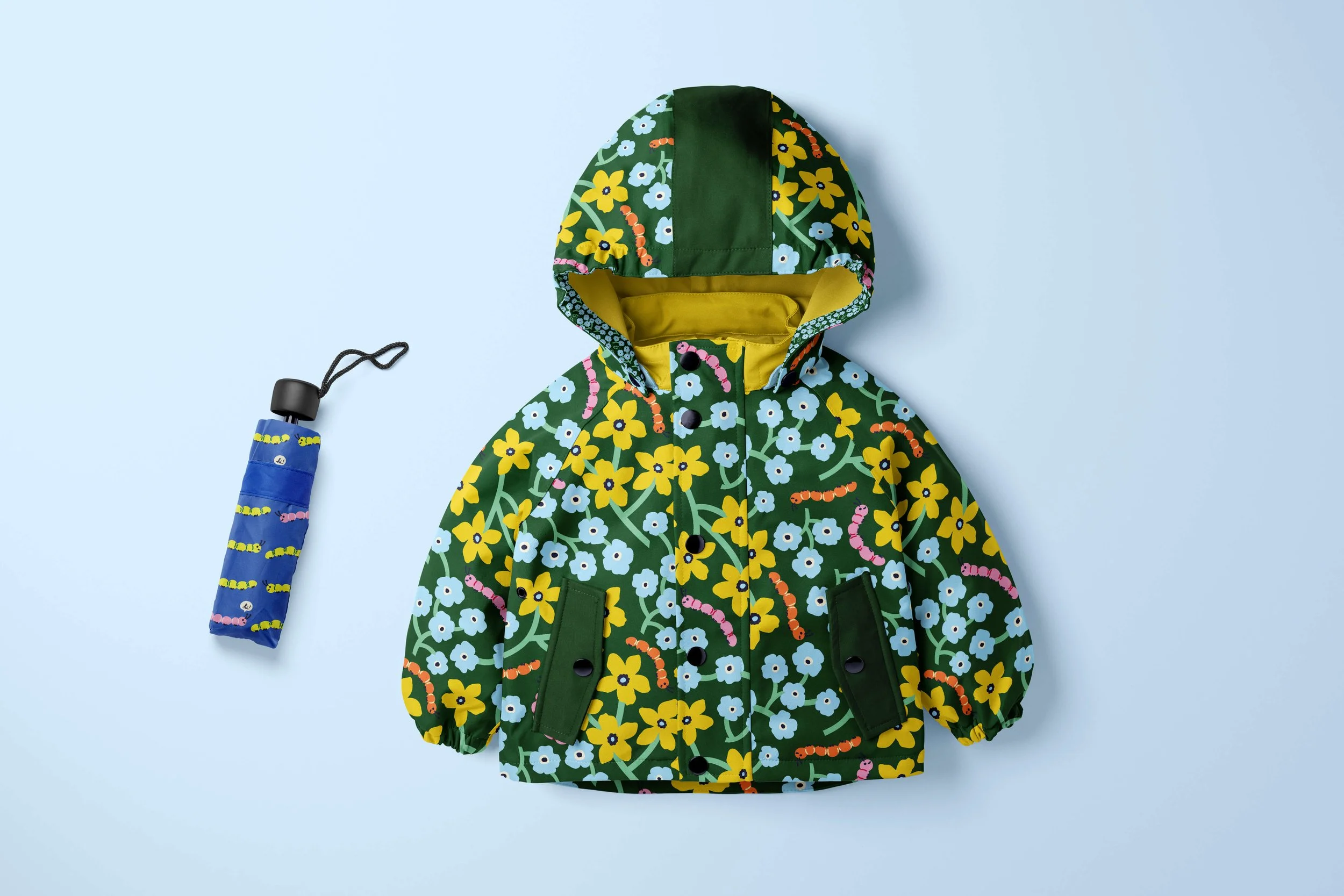 A children's rain jacket and umbrella featuring floral and caterpillar patterns.