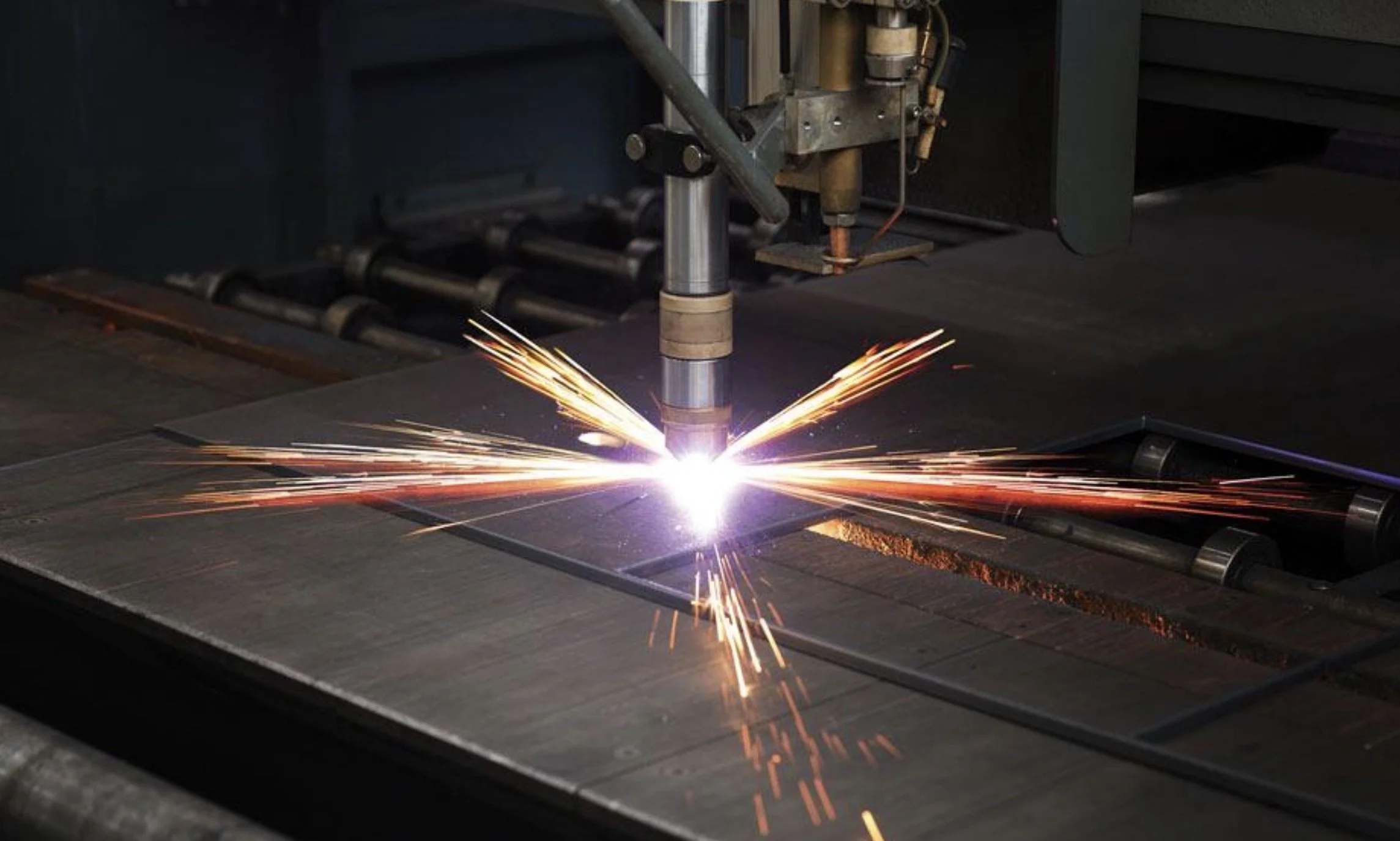 A welding machine welding metal, with sparks flying outward in a dark industrial setting.