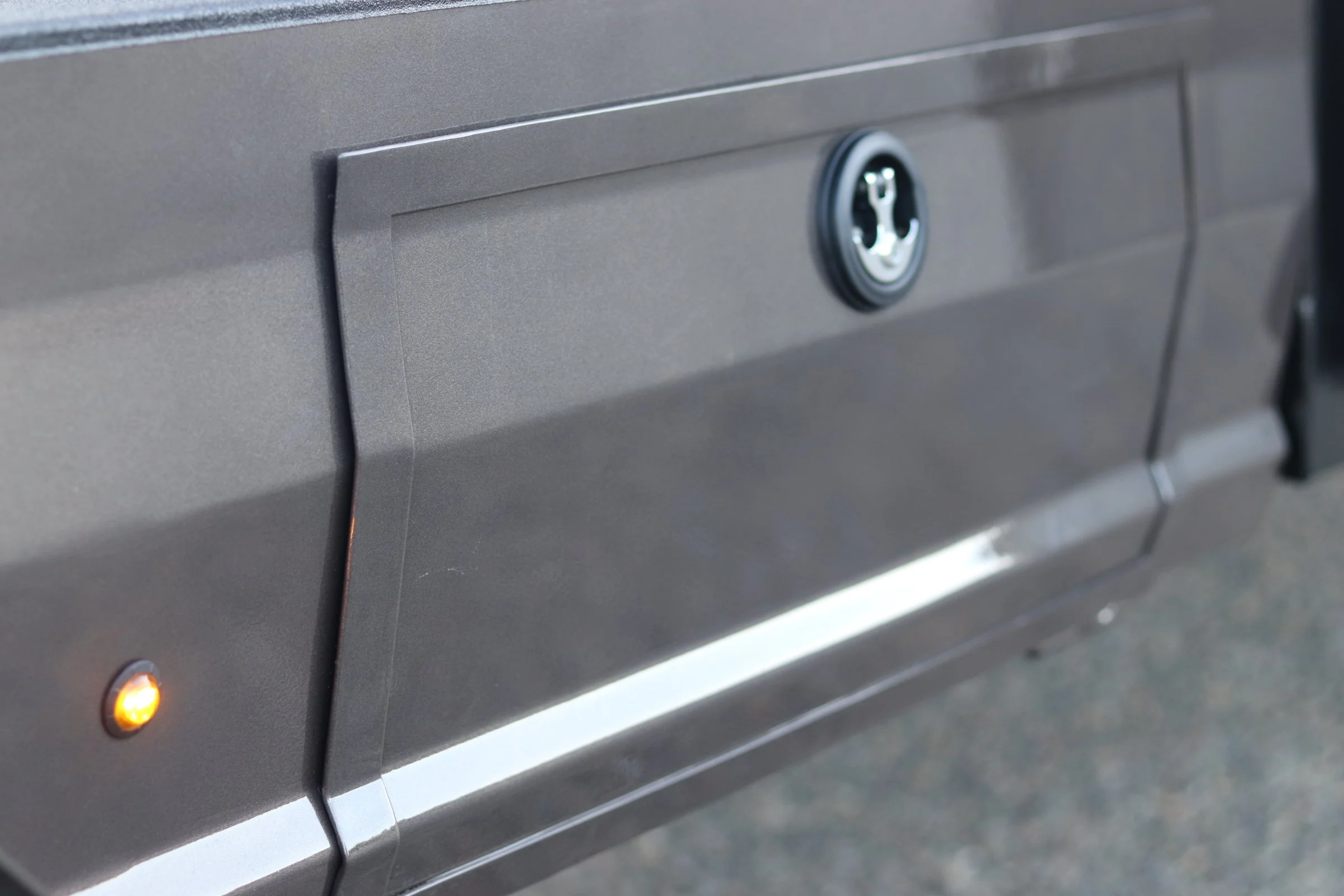 Close-up of a gray metal mailbox with a lock and a small orange indicator light.