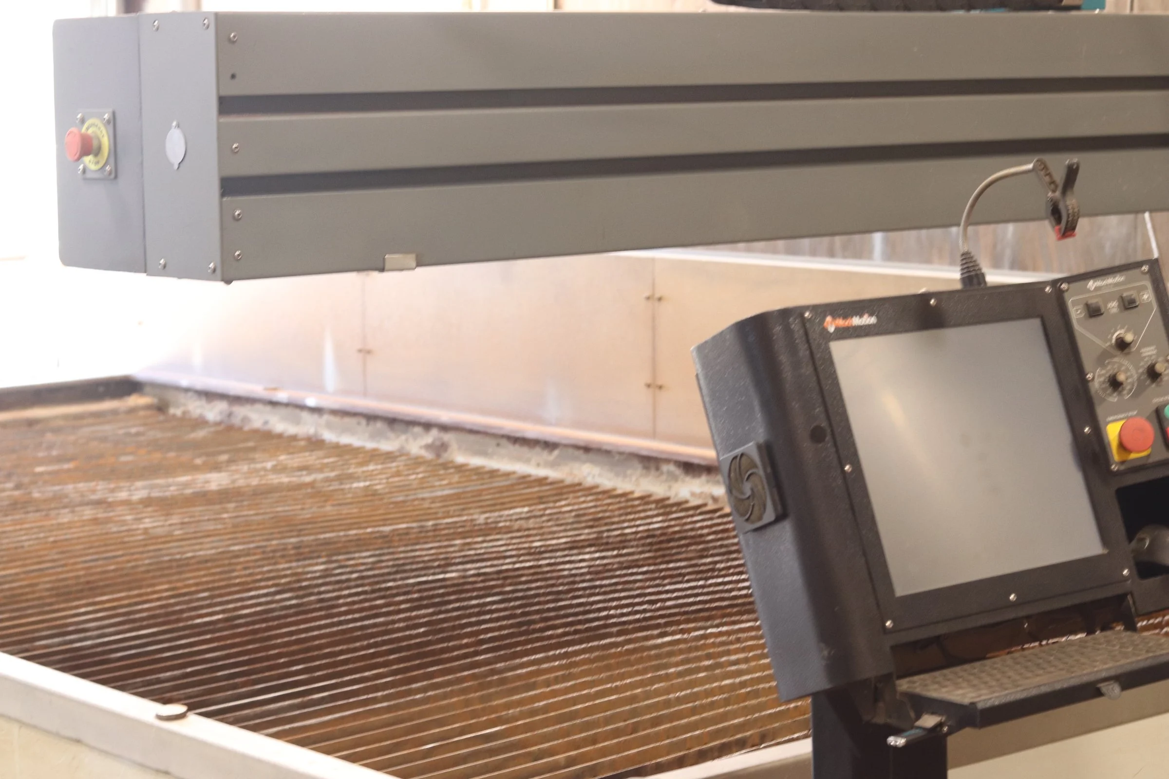 A large industrial water jet cutter machine with a control panel and a metal bed.