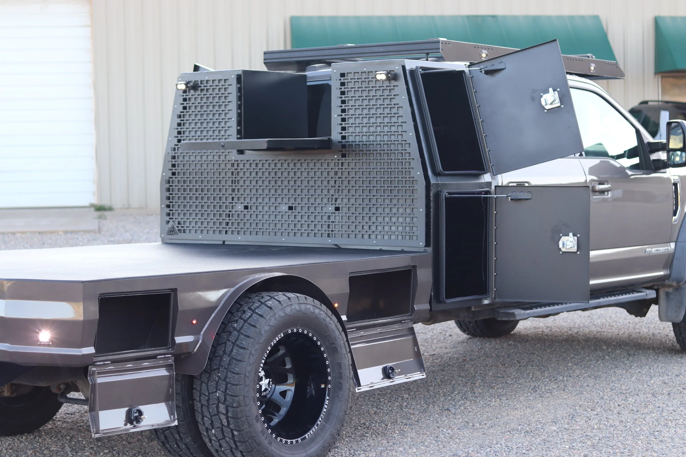 Modified pickup truck with black storage compartments and customizations in a parking lot.