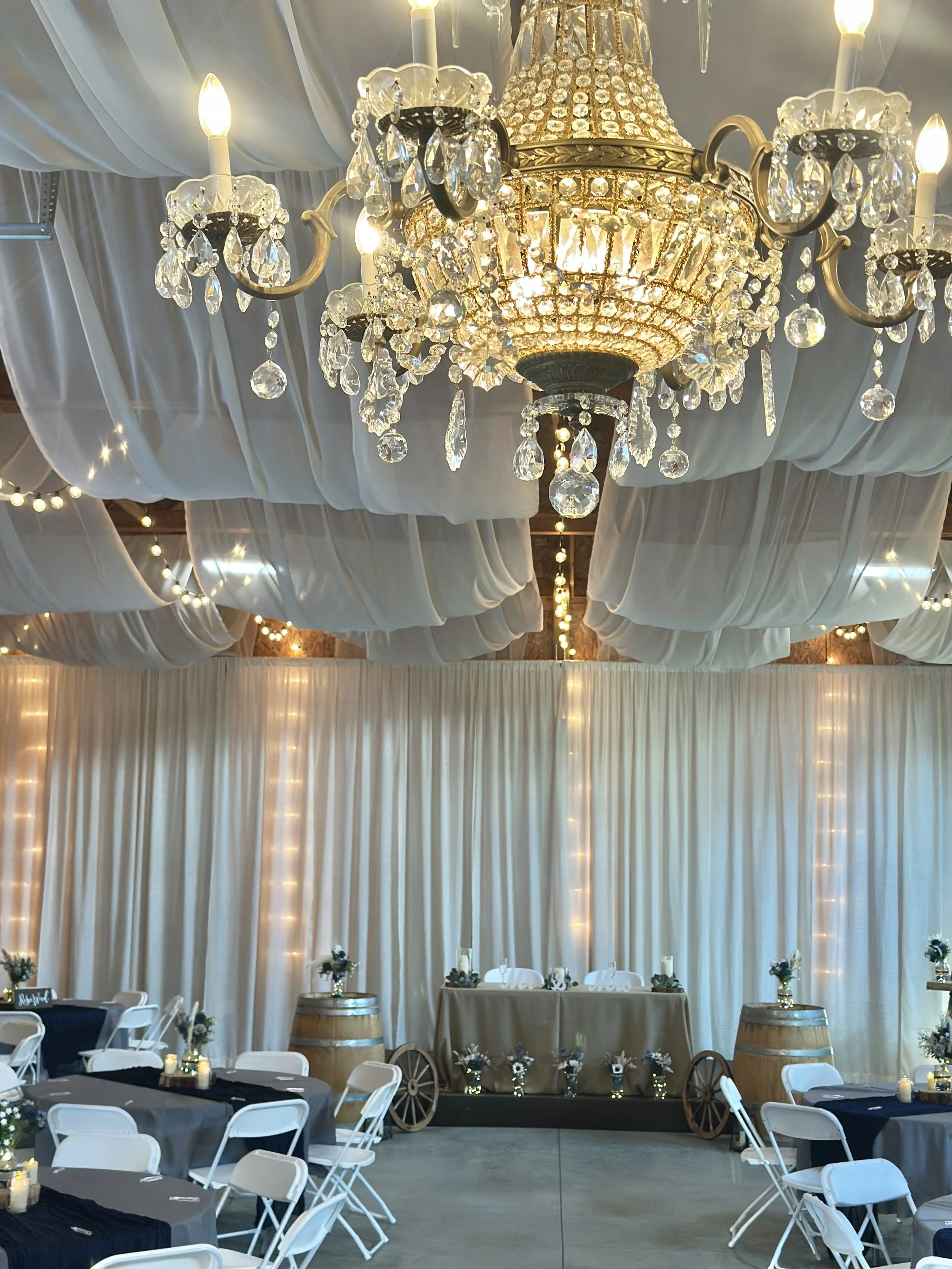 Crystal Chandelier wedding venue with whites drapes on the ceiling