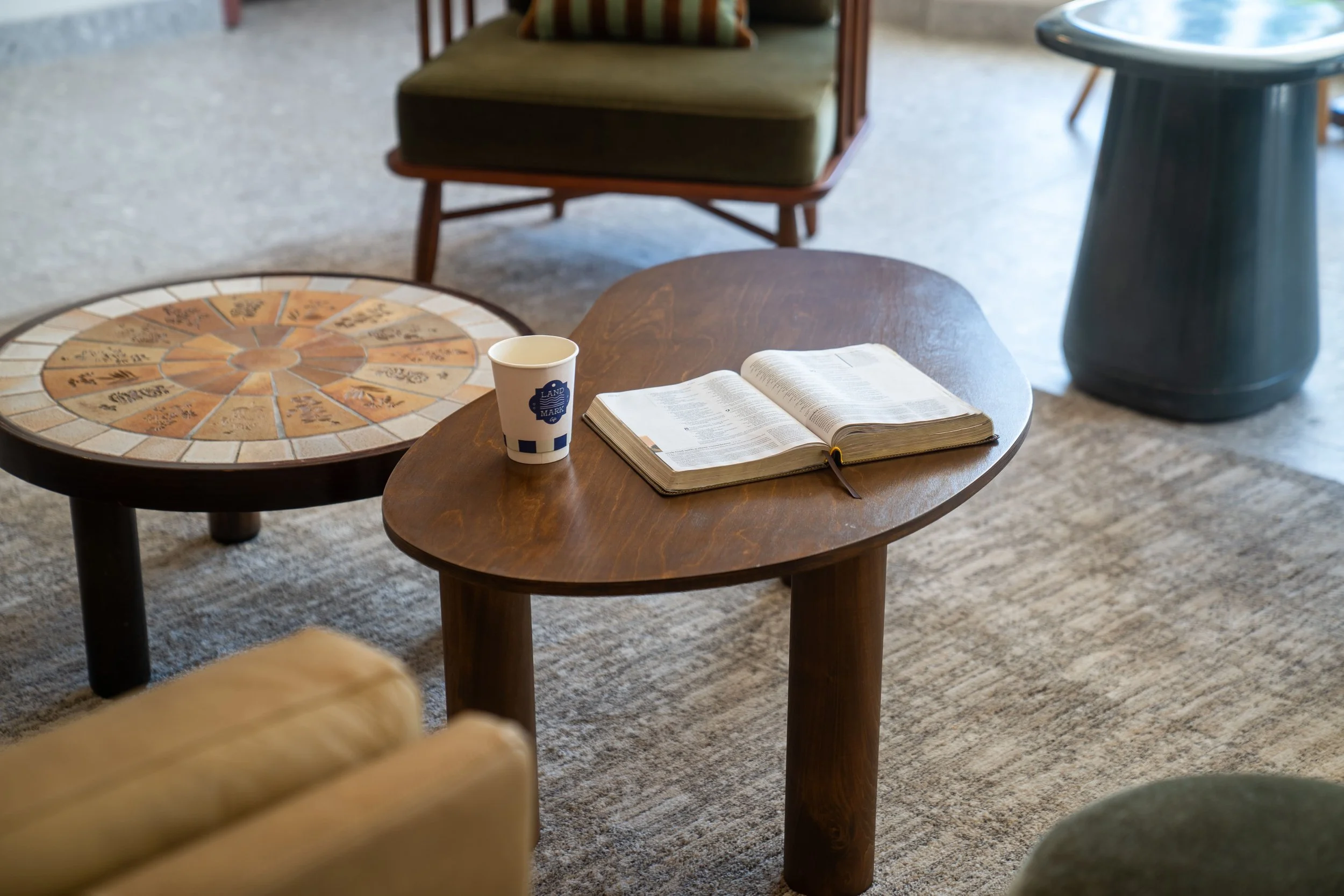 a paper landmark cafe coffee cup and open bible laying on top of a coffee table inside of landmark cafe