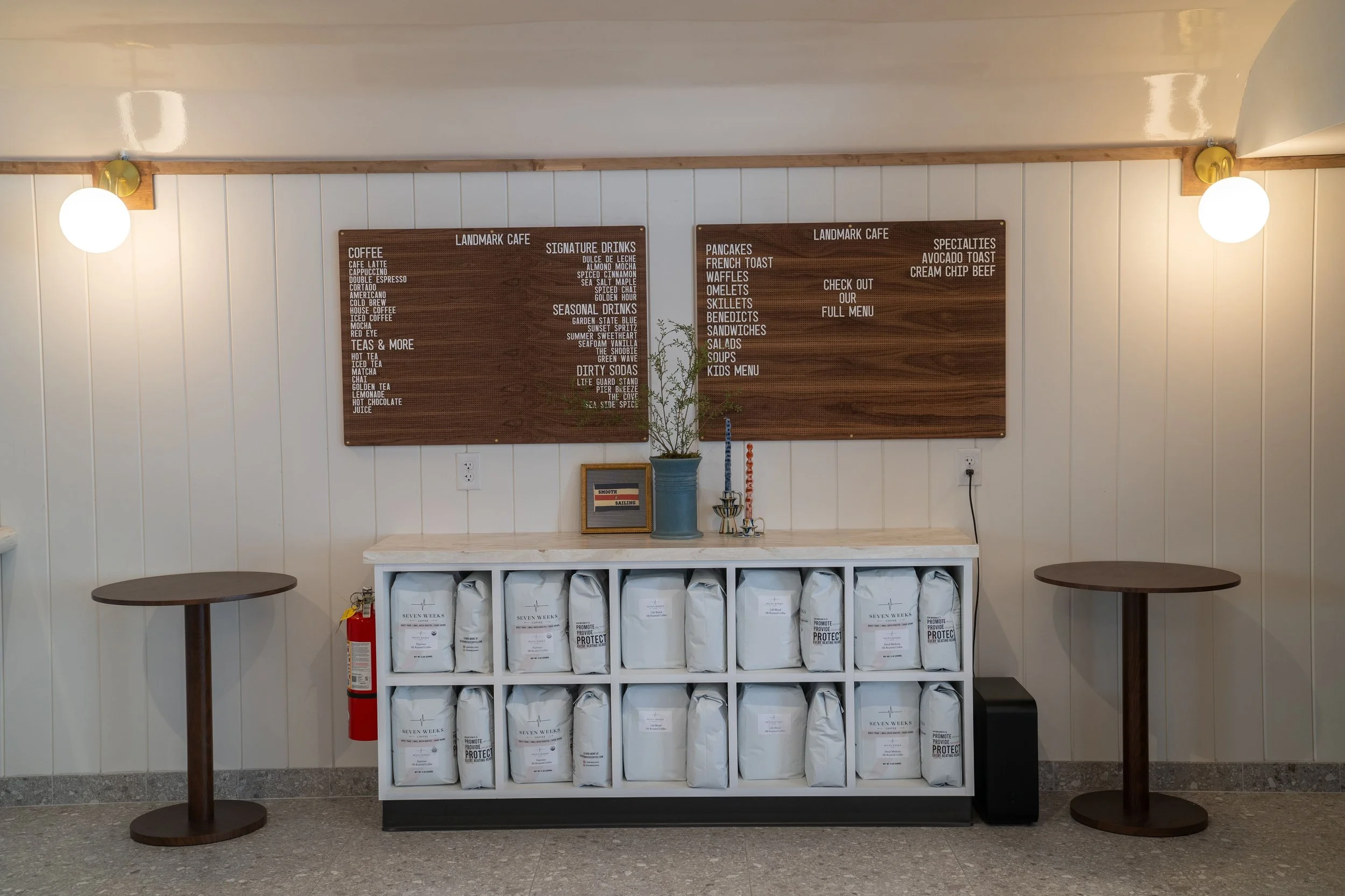 menu boards at landmark cafe hanging up on a wall with coffee bag storage underneath it