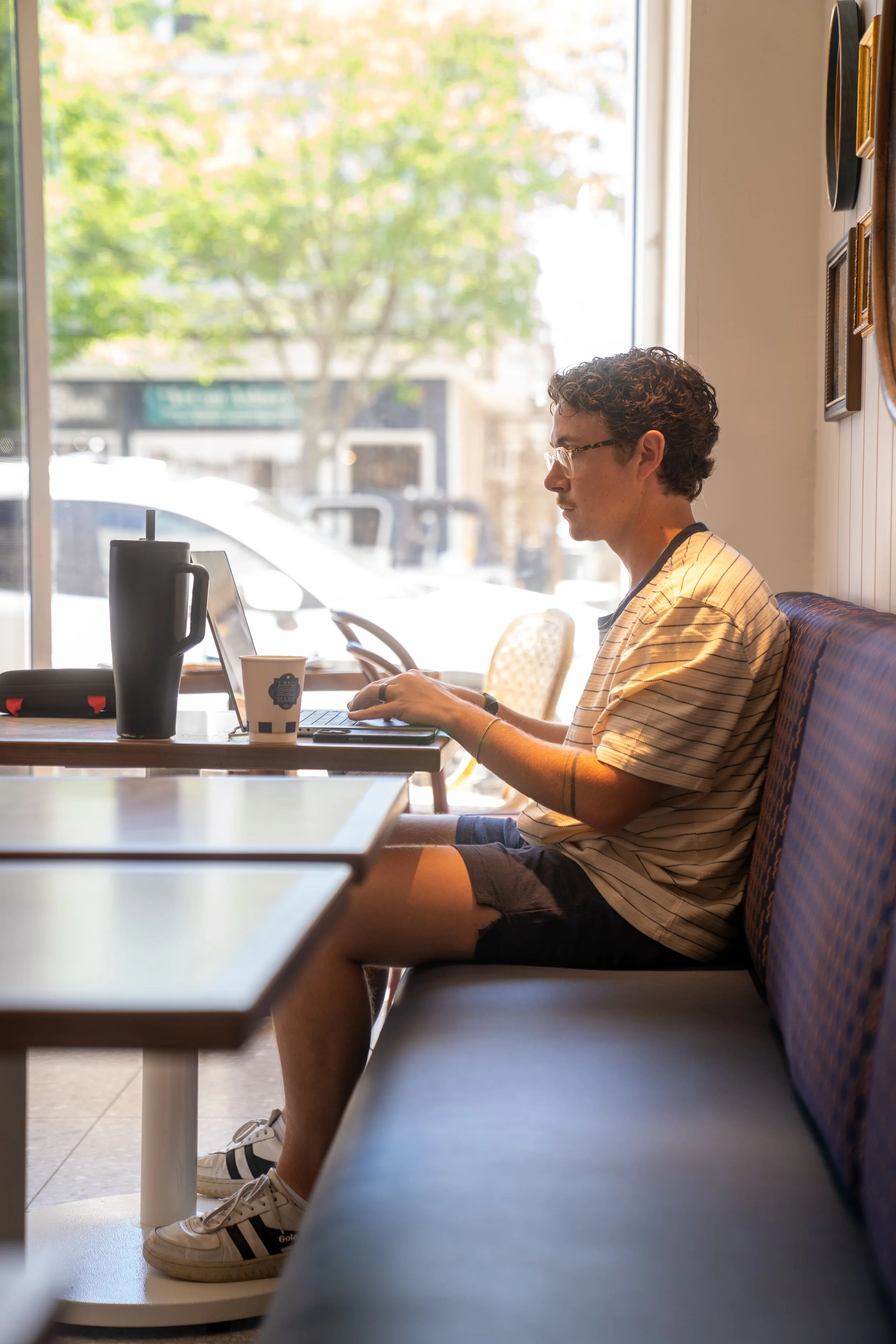 white male sitting at a table at landmark cafe on his computer