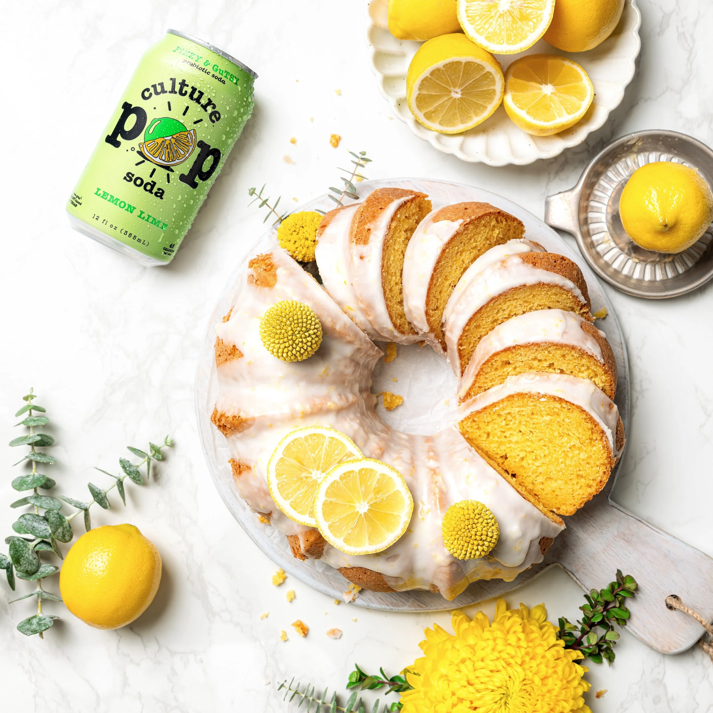 Editorial layout for a modern gut-health probiotic beverage brand. Artistically styled with fresh summer fruits, a gold cocktail spoon, a clear ice block, and botanical accents on a colorful backdrop for a CPG campaign.