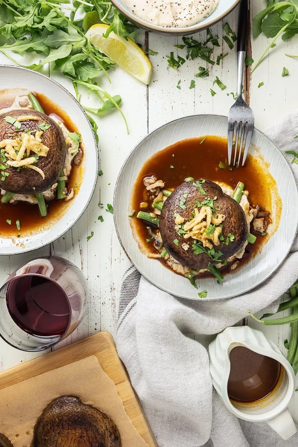 Food photography of a savory mushroom and bean purée dish with a rich red wine sauce drizzle and fresh herbs, featured as an elegant, rustic vegetarian recipe on the JodiLoves food blog.