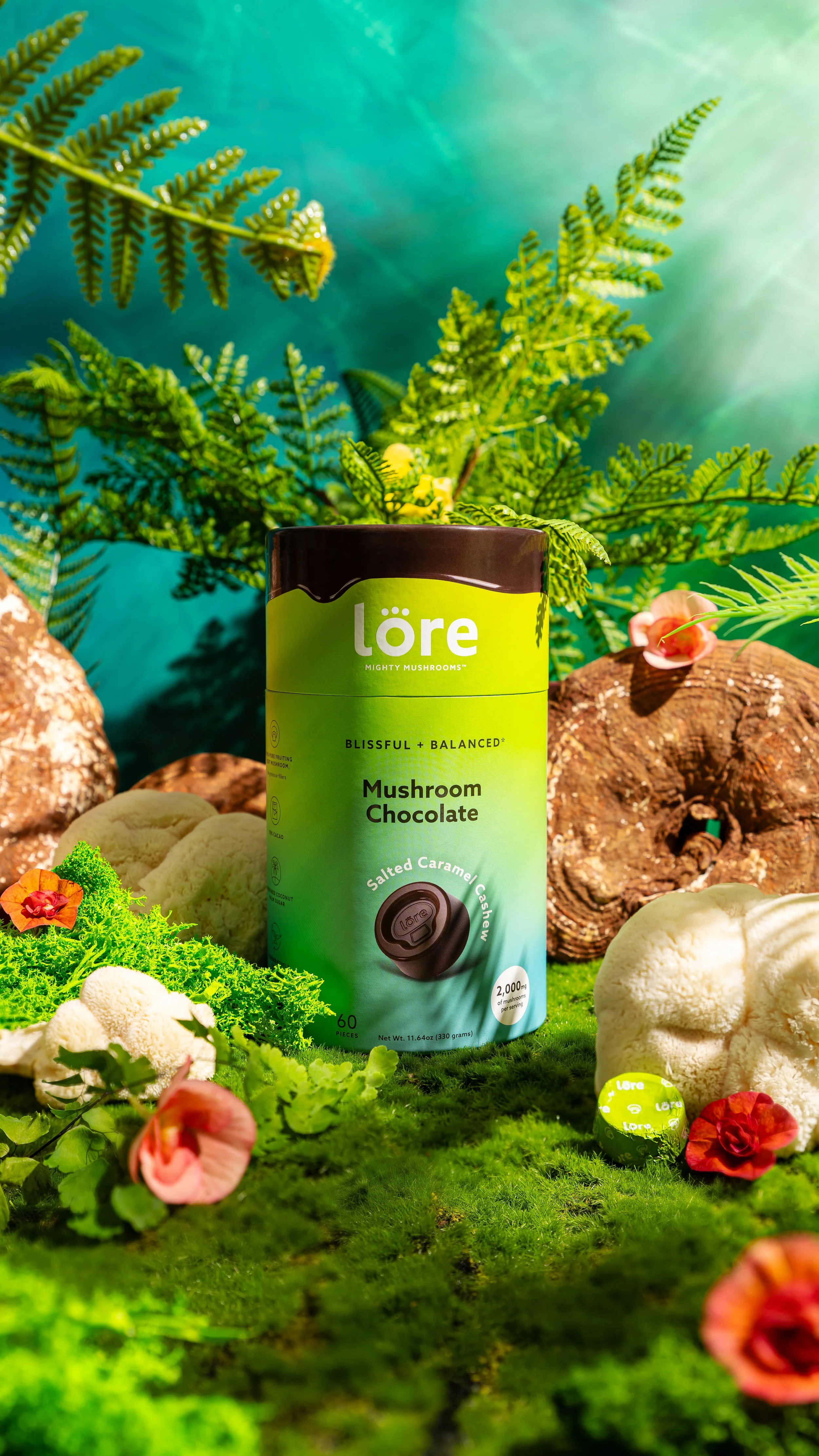 Product photography for Lore Mighty Mushrooms salted caramel cashew chocolates. The container is styled with mushrooms, moss, and ferns under dramatic jungle floor lighting with harsh and diffused sunlight.