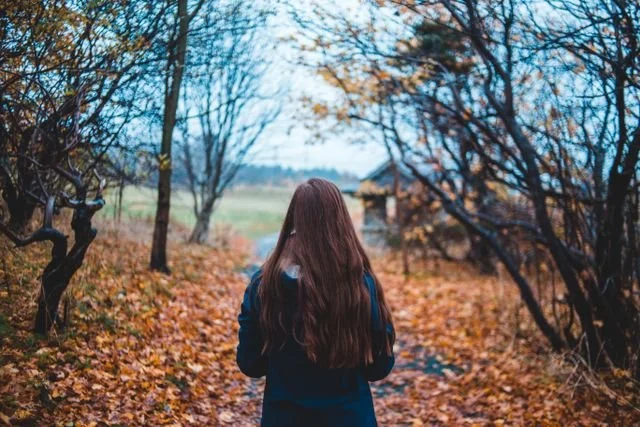 a woman outside in the falling yellow leaves of fall