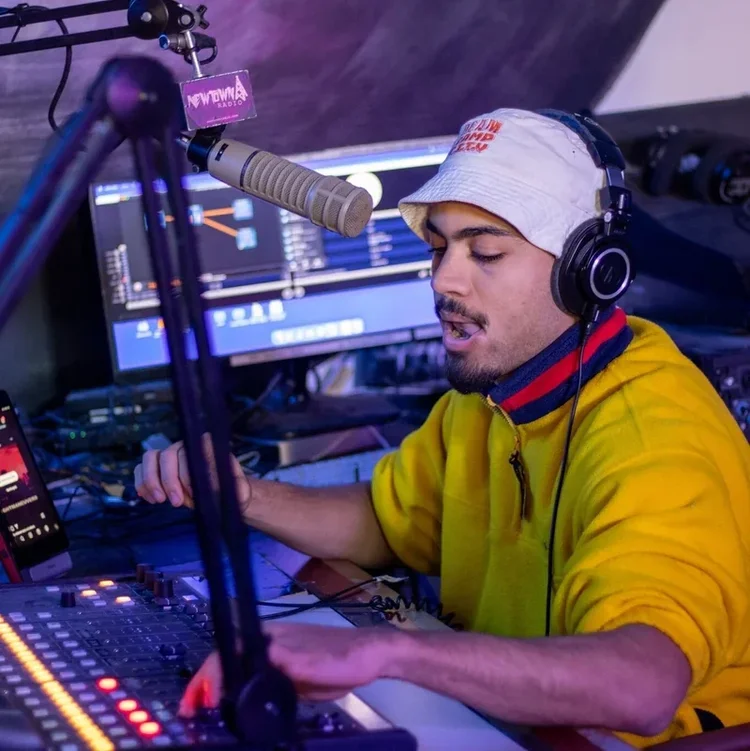 A bbLeaders fellow at the mic and mixing board in a radio studio