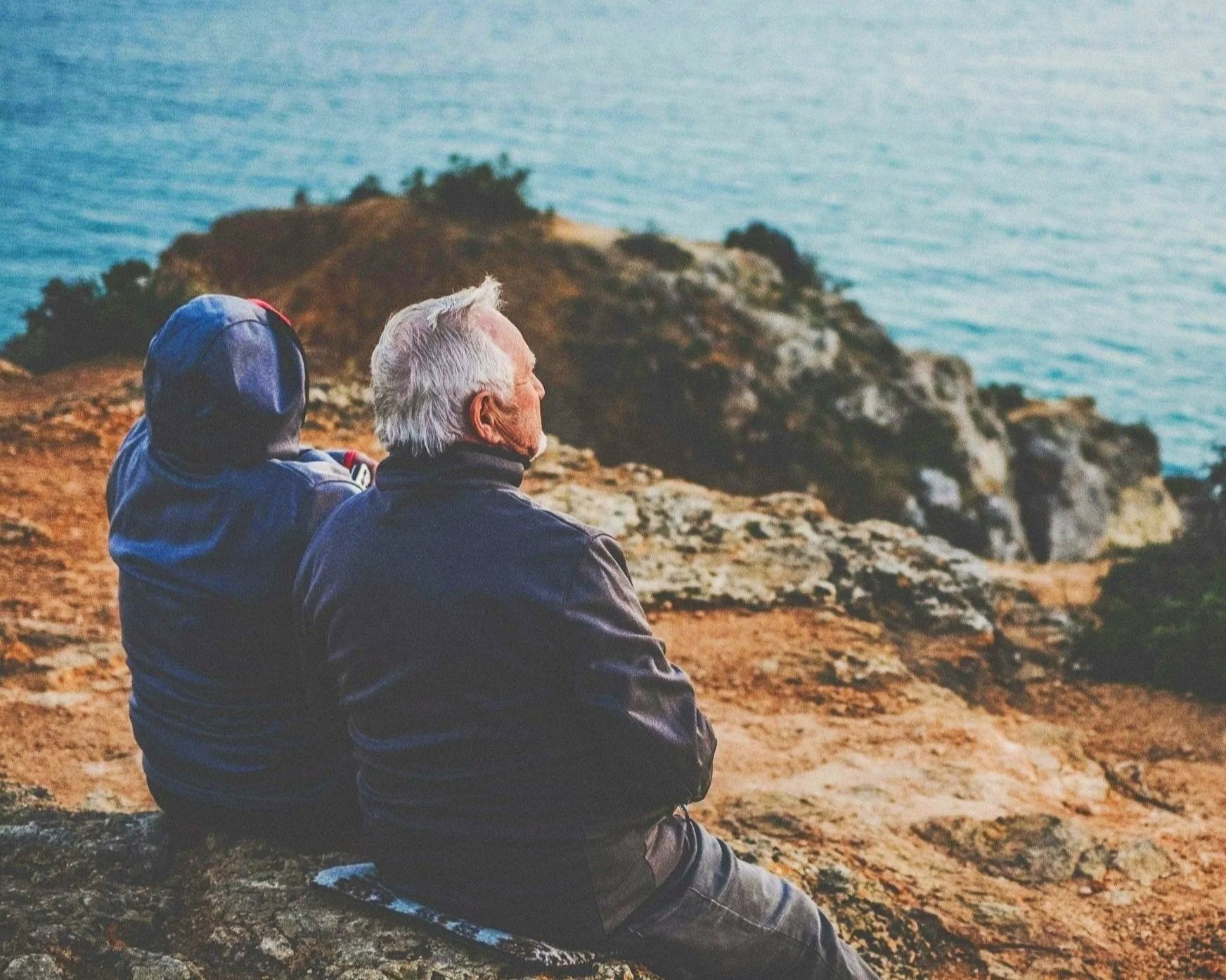 Older couple sitting on rocks, looking out to sea