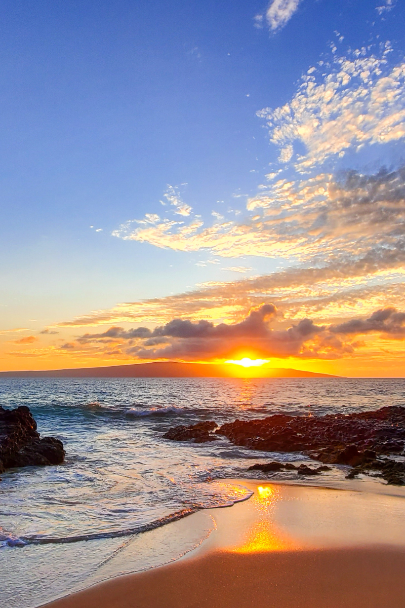 Sunset over the rocky shoreline at Secret Beach on Maui
