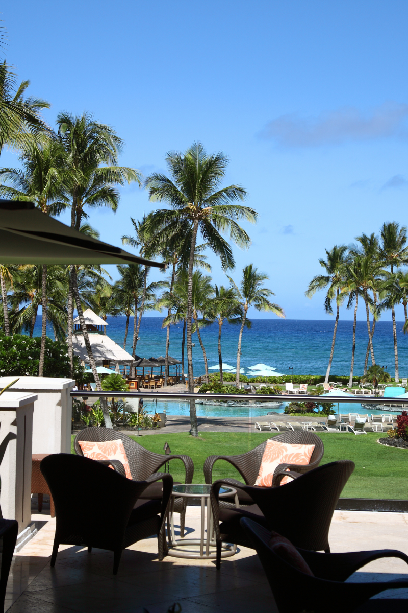 Resort terrace overlooking palm trees, swimming pools and the ocean on the Big Island