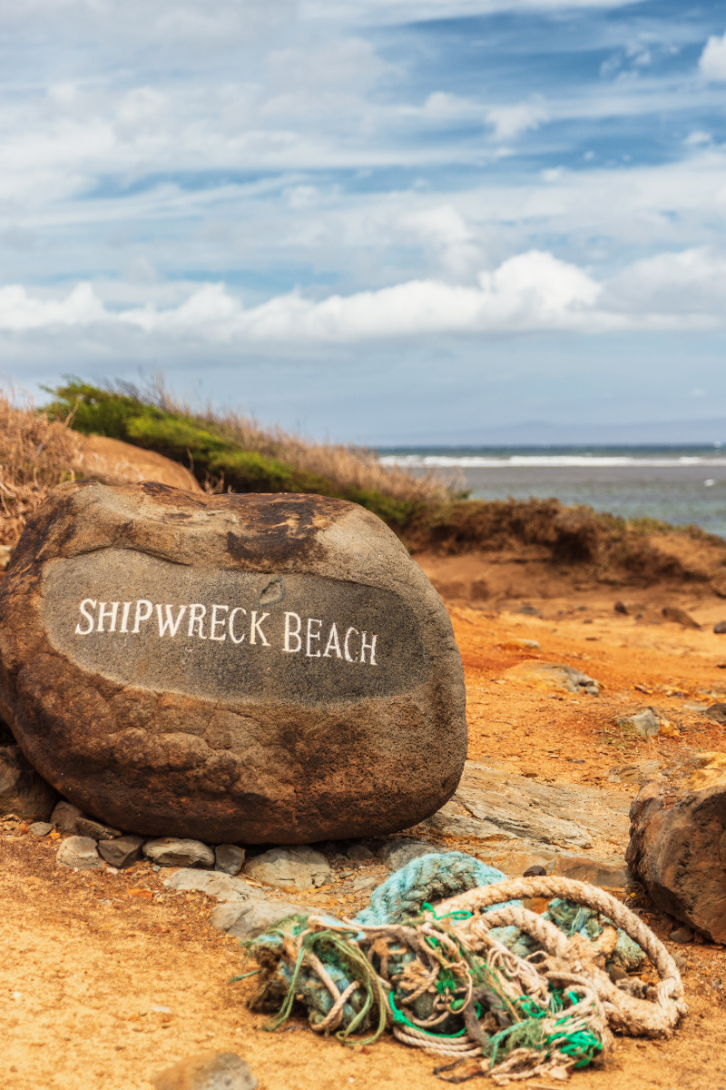 Shipwreck Beach marker on a rock beside coiled rope on Lanai