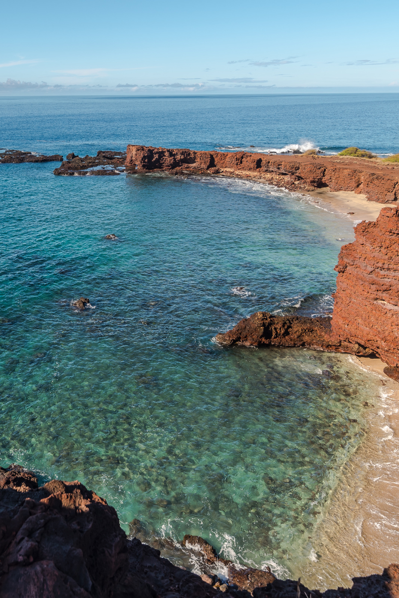 Clear turquoise water along Lanai’s red-rock coastline