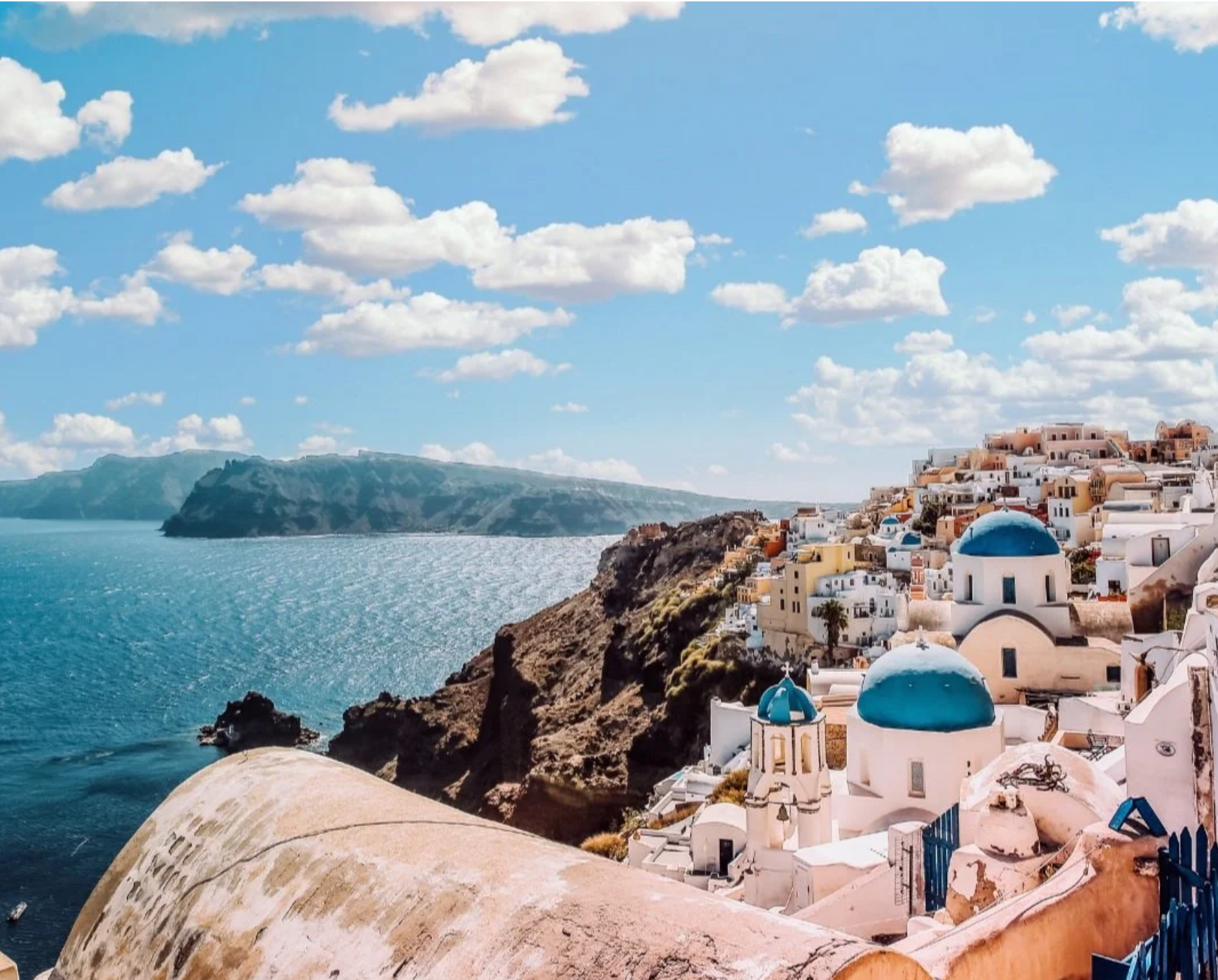 Santorini island in Greece with whitewashed buildings and blue domes overlooking the Aegean Sea and dramatic coastal cliffs.