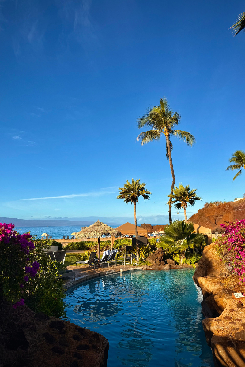 Tropical resort bliss in West Maui, featuring a lagoon-style pool framed by vibrant bougainvillea and ocean views.