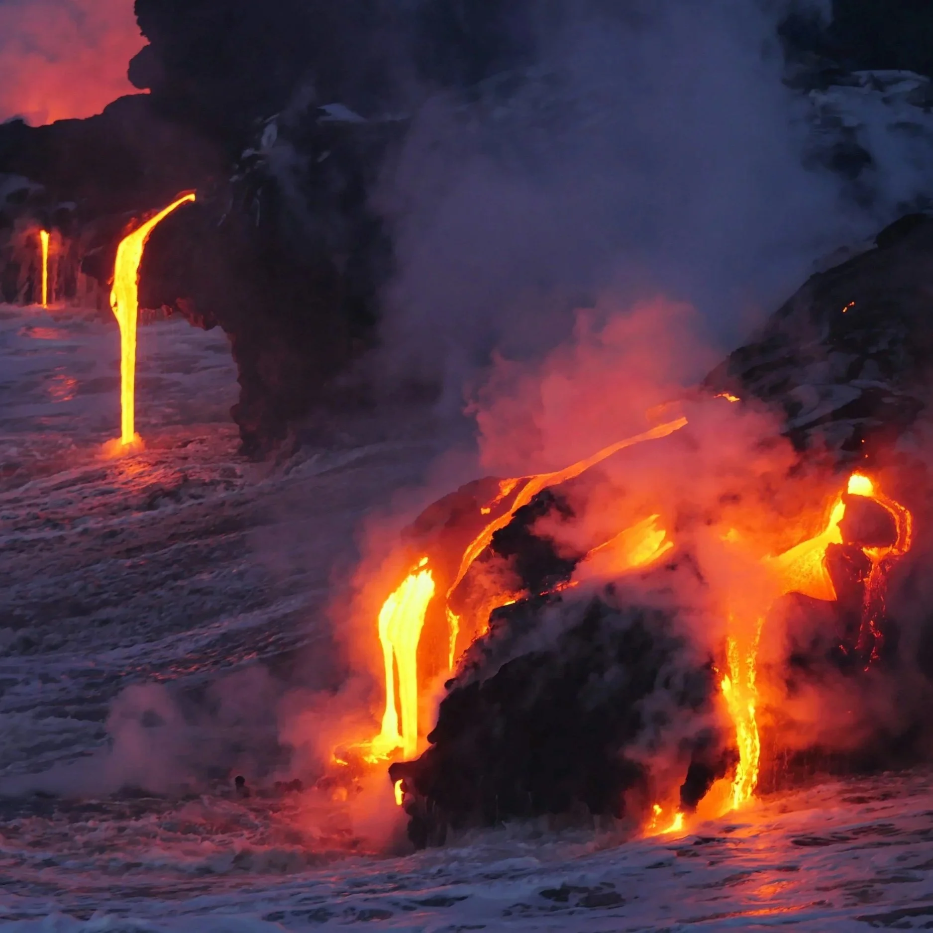 Glowing lava flowing into the ocean at Hawaiʻi Volcanoes National Park on the Big Island of Hawaii.