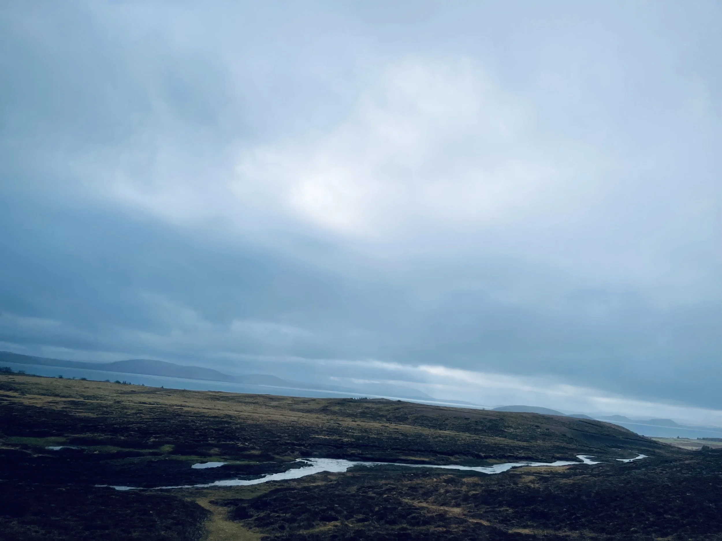 Clouds over Iceland’s open landscape and winding water, photographed by Jeanine