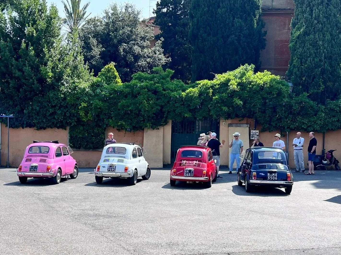 A line of colorful vintage Fiat 500 cars parked in a sun-drenched Italian courtyard, representing unique destination experiences.