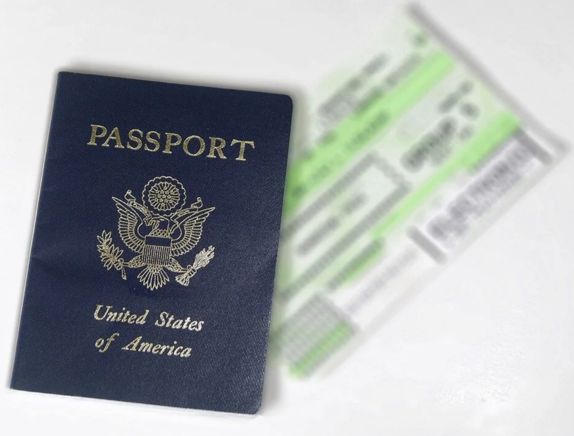 A dark blue United States of America passport sitting next to blurred airline boarding passes on a white background
