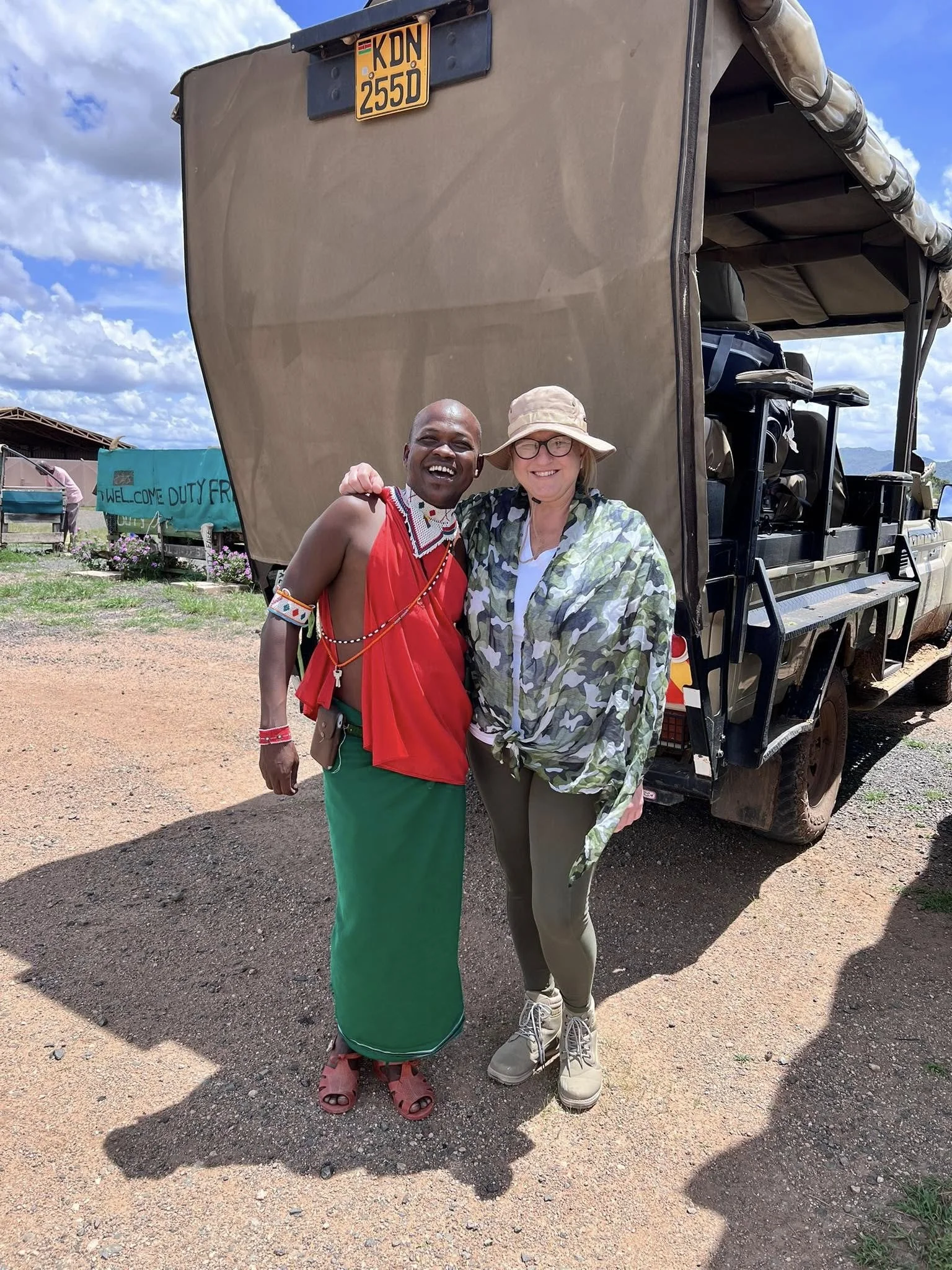 Professional travel expert, Jeanine, on a luxury African safari in 2025, posing with a local Maasai guide.
