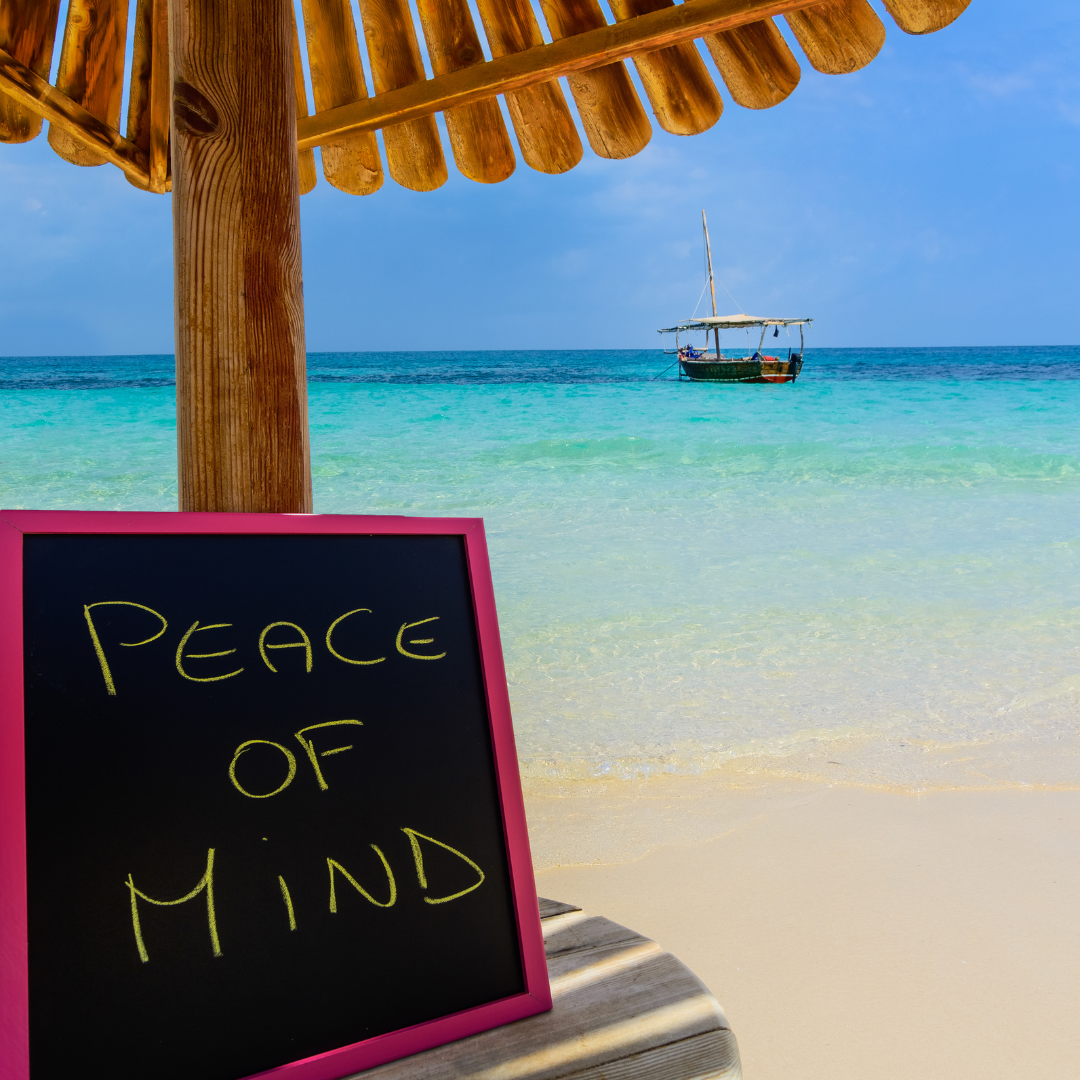 Tropical beach scene featuring a "Peace of Mind" sign, clear blue water, and a traditional boat, representing the ultimate vacation relaxation.