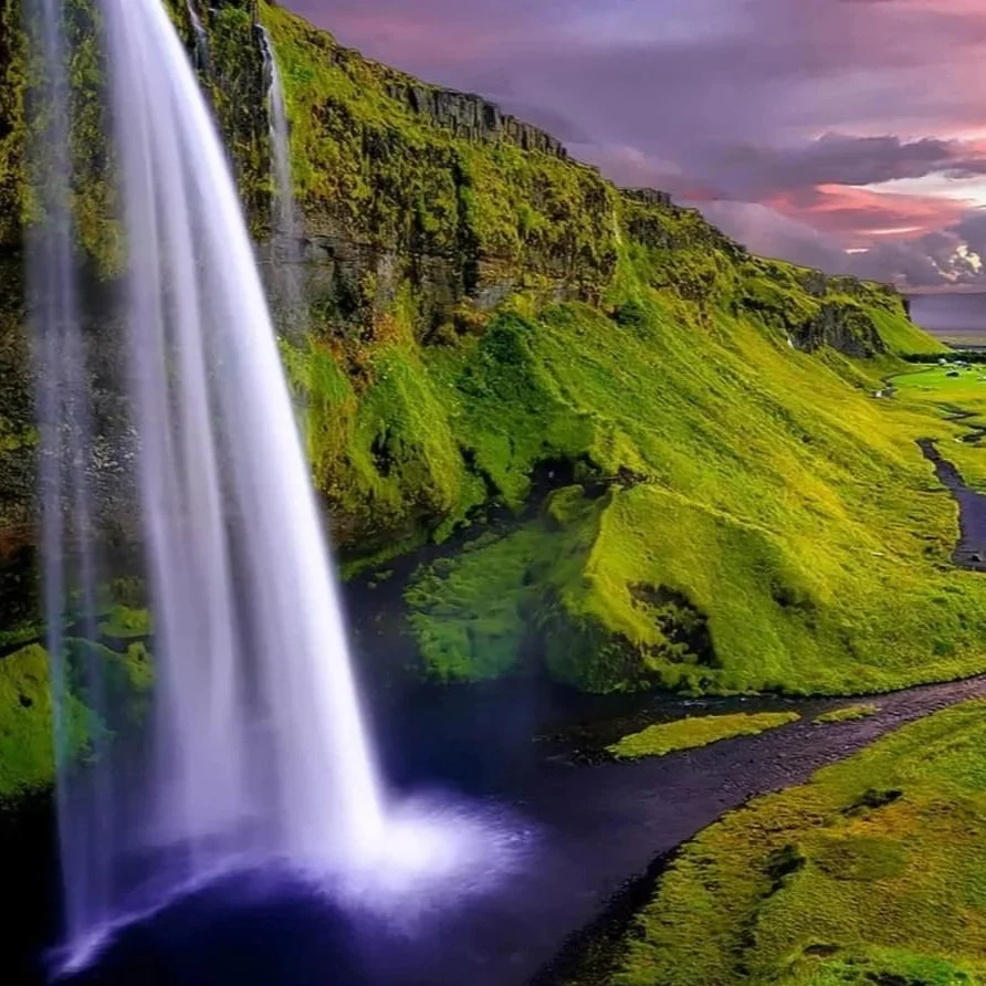 Long exposure of Seljalandsfoss waterfall in Iceland with lush green cliffs, illustrating custom adventure travel planning.