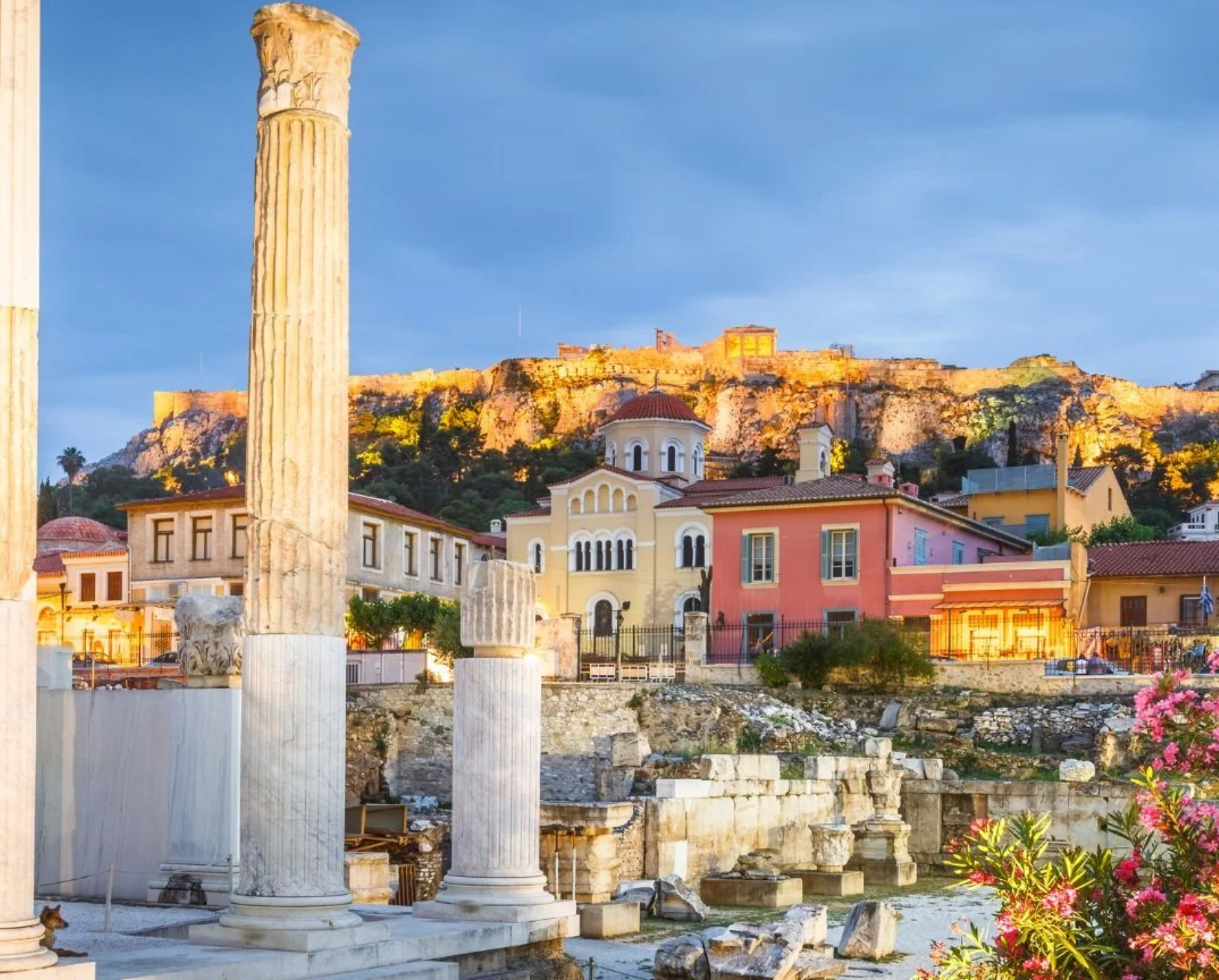 Acropolis of Athens at sunset overlooking historic Plaka neighborhood, with ancient ruins and colorful buildings in Greece.
