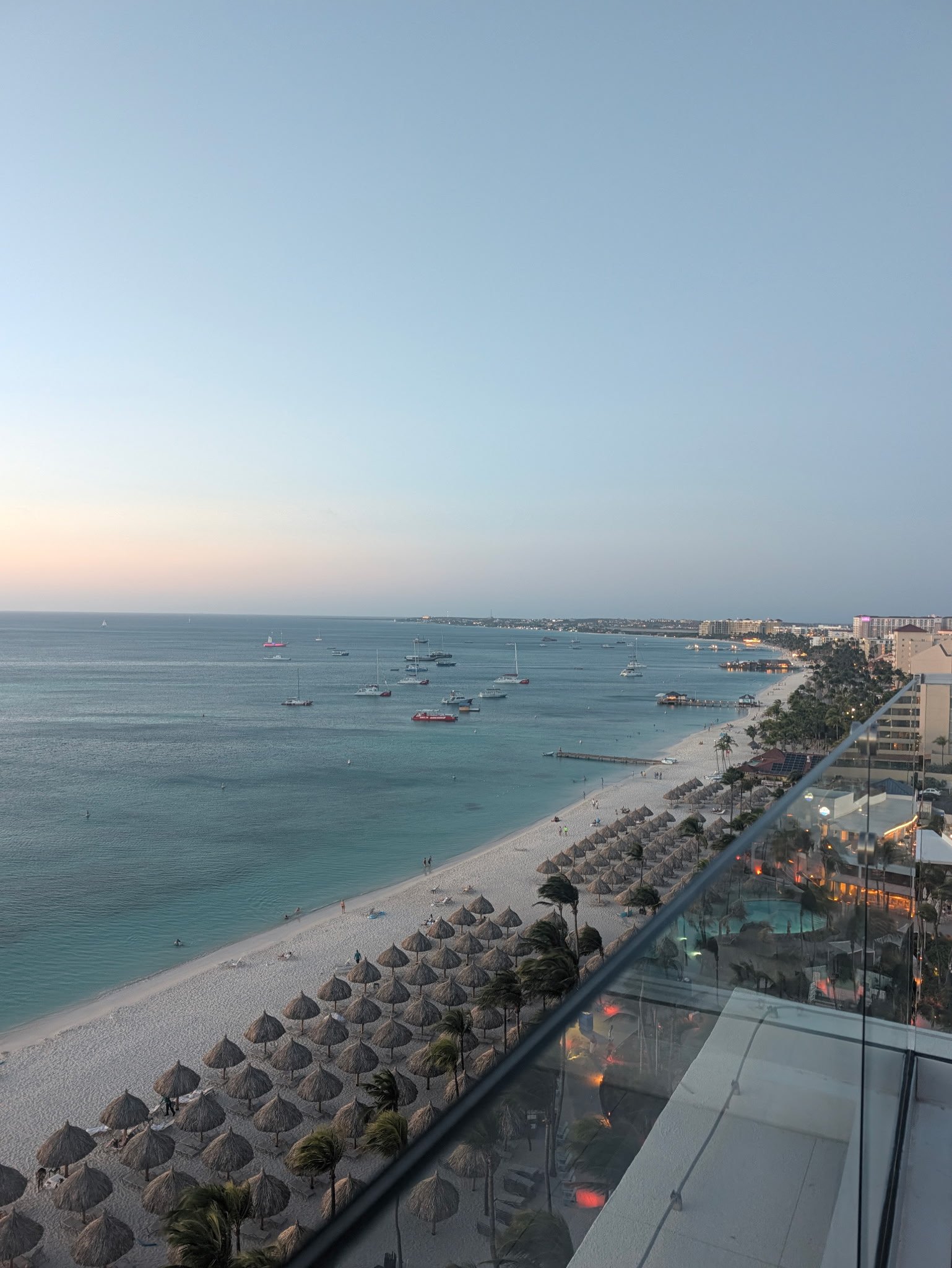 High-rise resort hotels lining the curve of Palm Beach along calm turquoise Caribbean water in Aruba