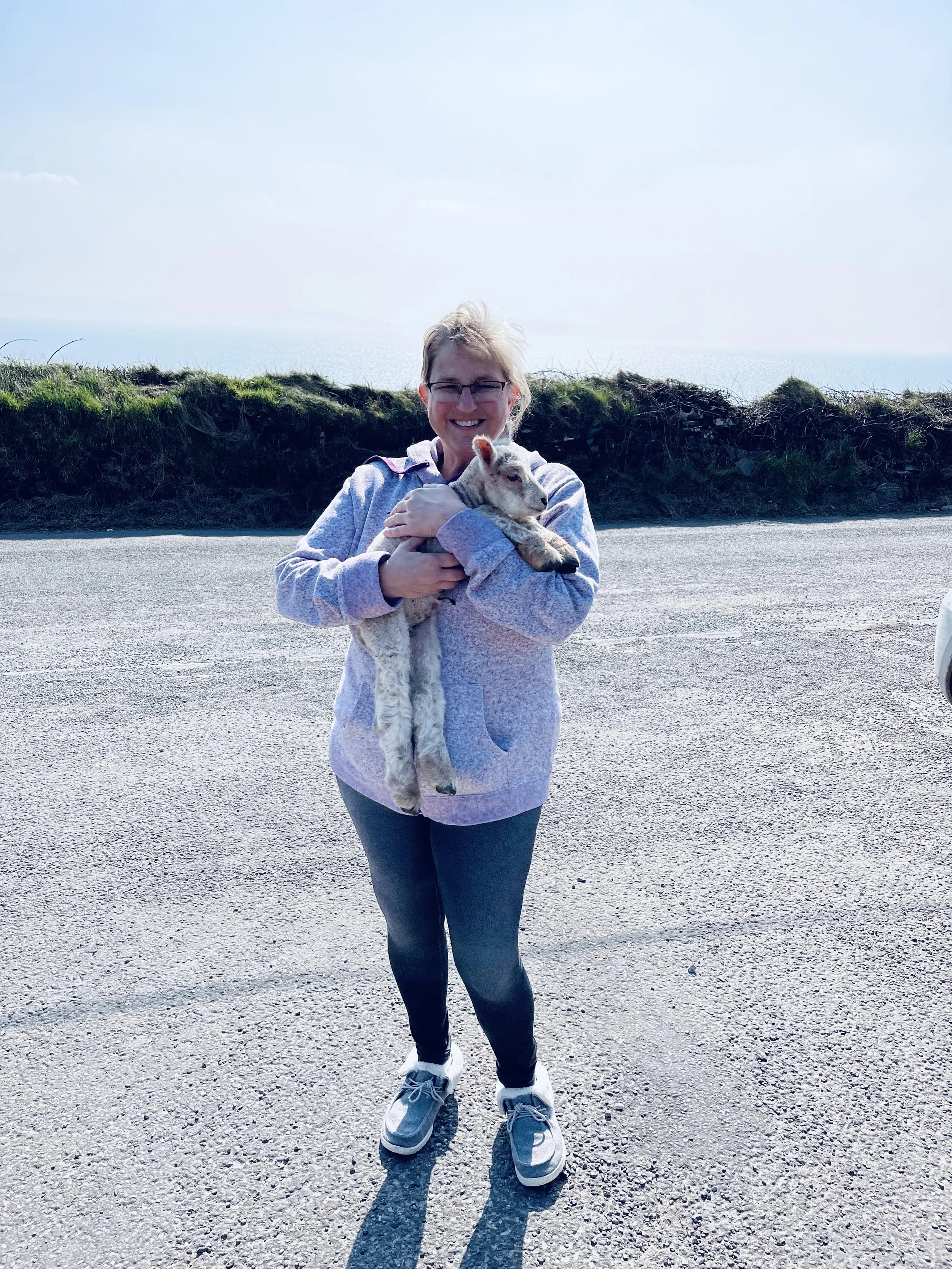 Jeanine with Lavishly Travel holding a baby newborn lamb in Ireland